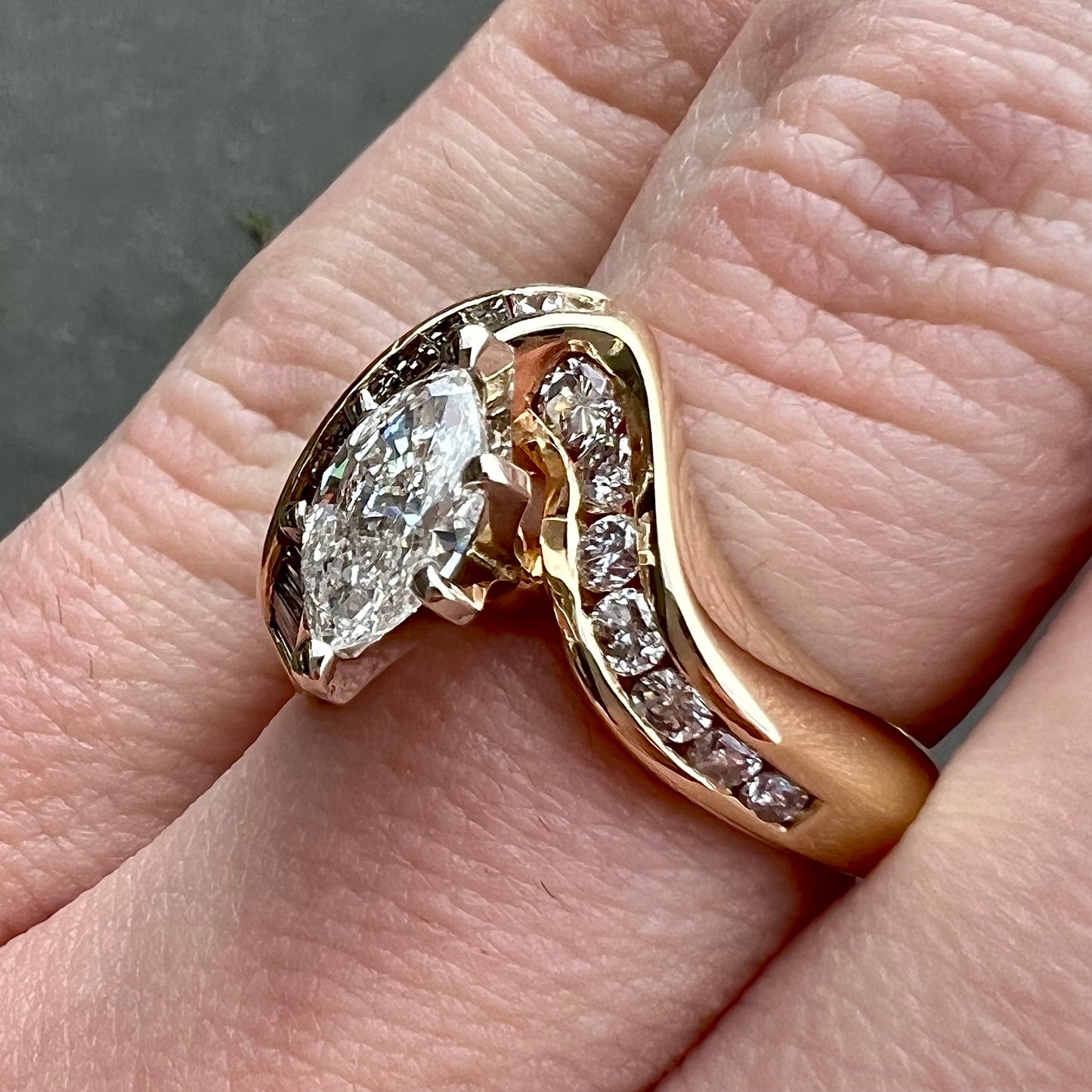 A ladies' marquise cut diamond engagement ring set with round and tapered baguette cut diamond accents.