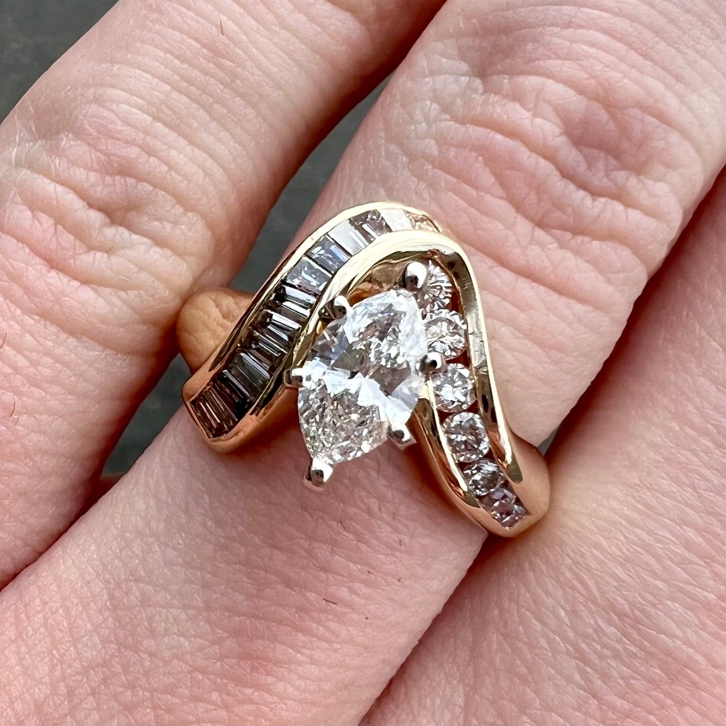 A ladies' marquise cut diamond engagement ring set with round and tapered baguette cut diamond accents.