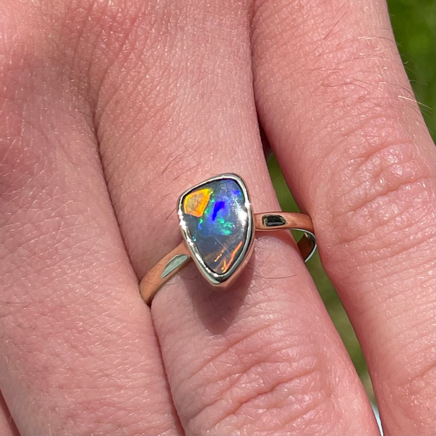 A handmade yellow gold solitaire ring bezel set with a Lightning Ridge red-on-black harlequin opal.