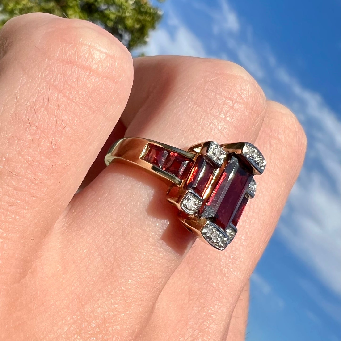 An Art Deco style emerald cut garnet and diamond ring cast in yellow gold.