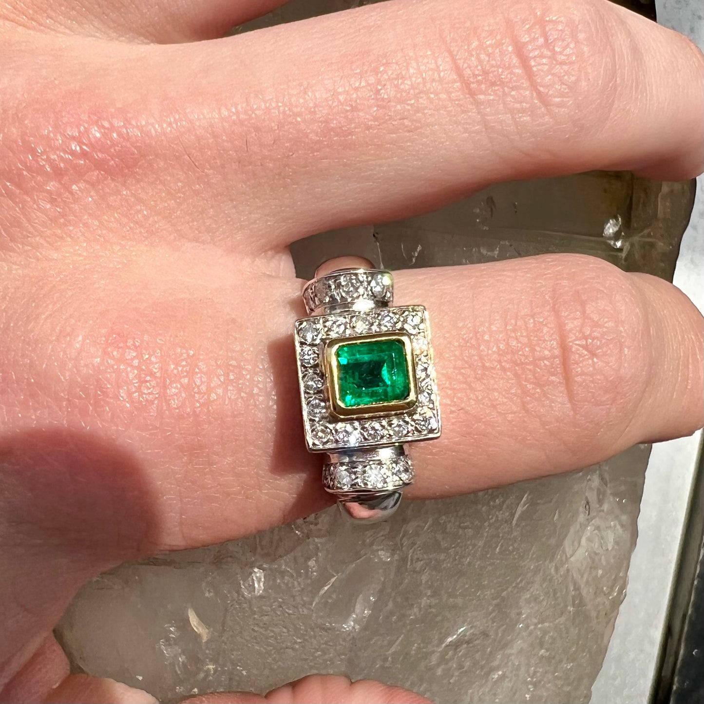 A two tone gold emerald and diamond halo ring.