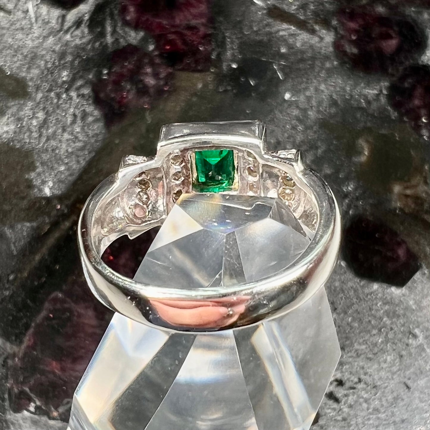A two tone gold emerald and diamond halo ring.