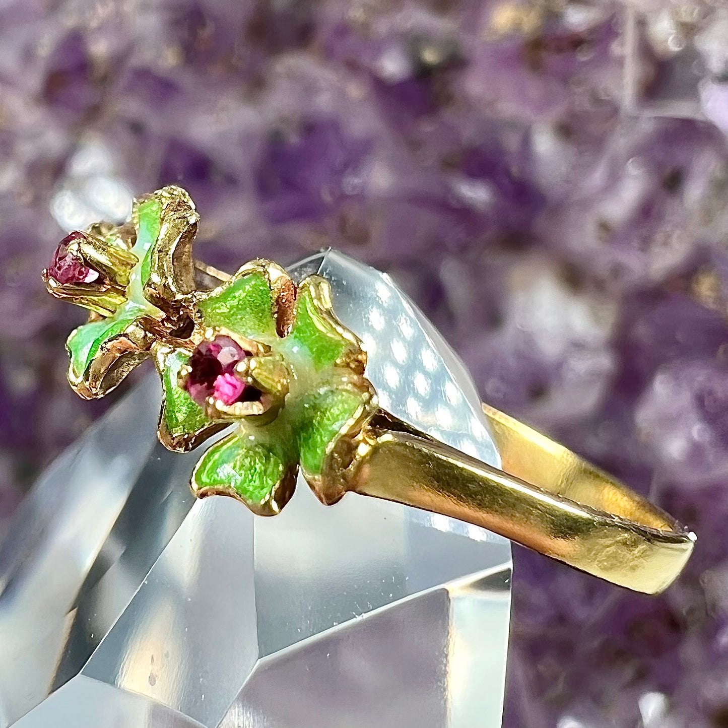 A gold ladies' ring in the motif of three flowers set with round ruby centers and green enameled petals.