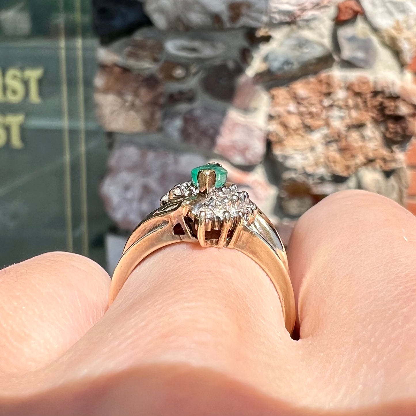 A yellow gold marquise cut emerald and diamond ring. The diamonds are prong set round cuts and channel set baguette cuts.