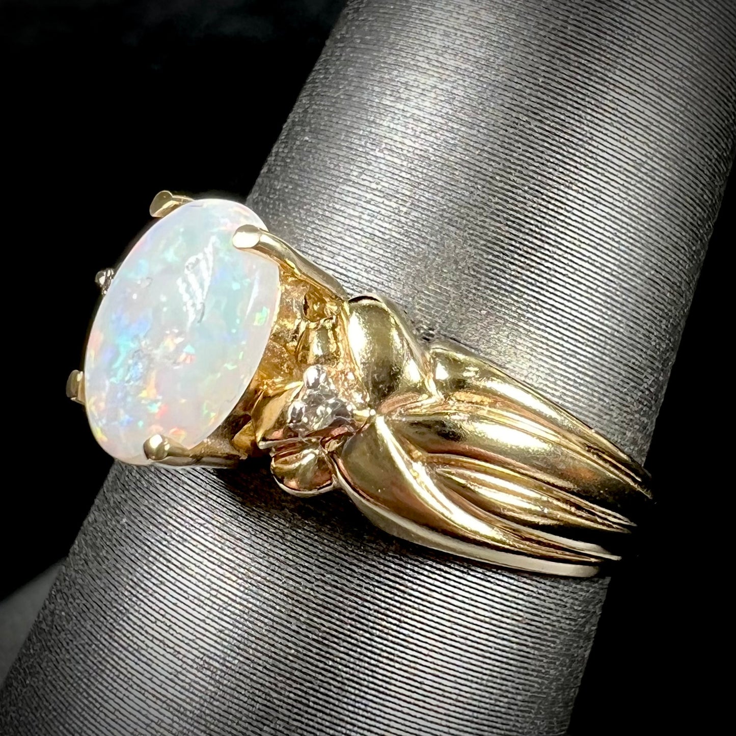 A ladies' yellow gold white crystal opal and diamond ring. The opal is prong set.