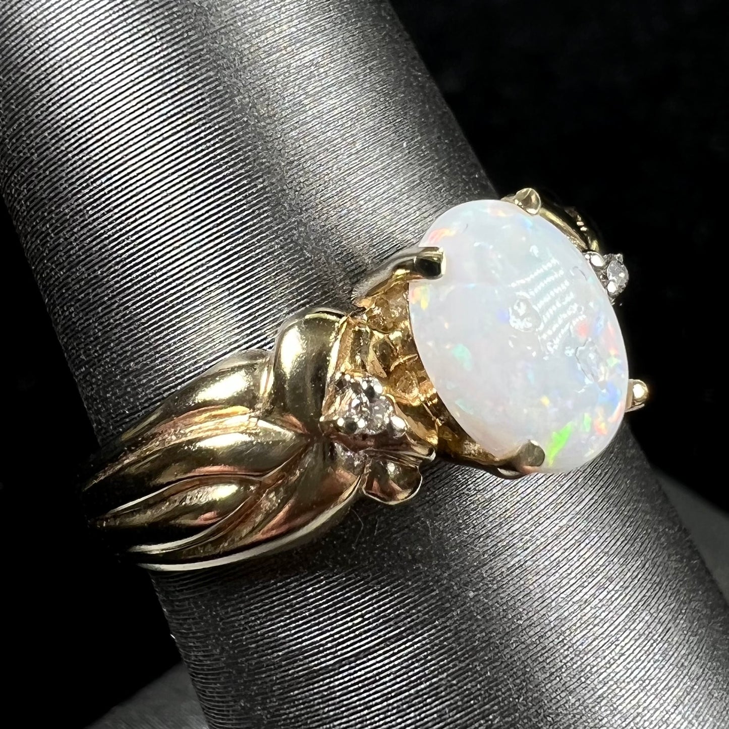 A ladies' yellow gold white crystal opal and diamond ring. The opal is prong set.