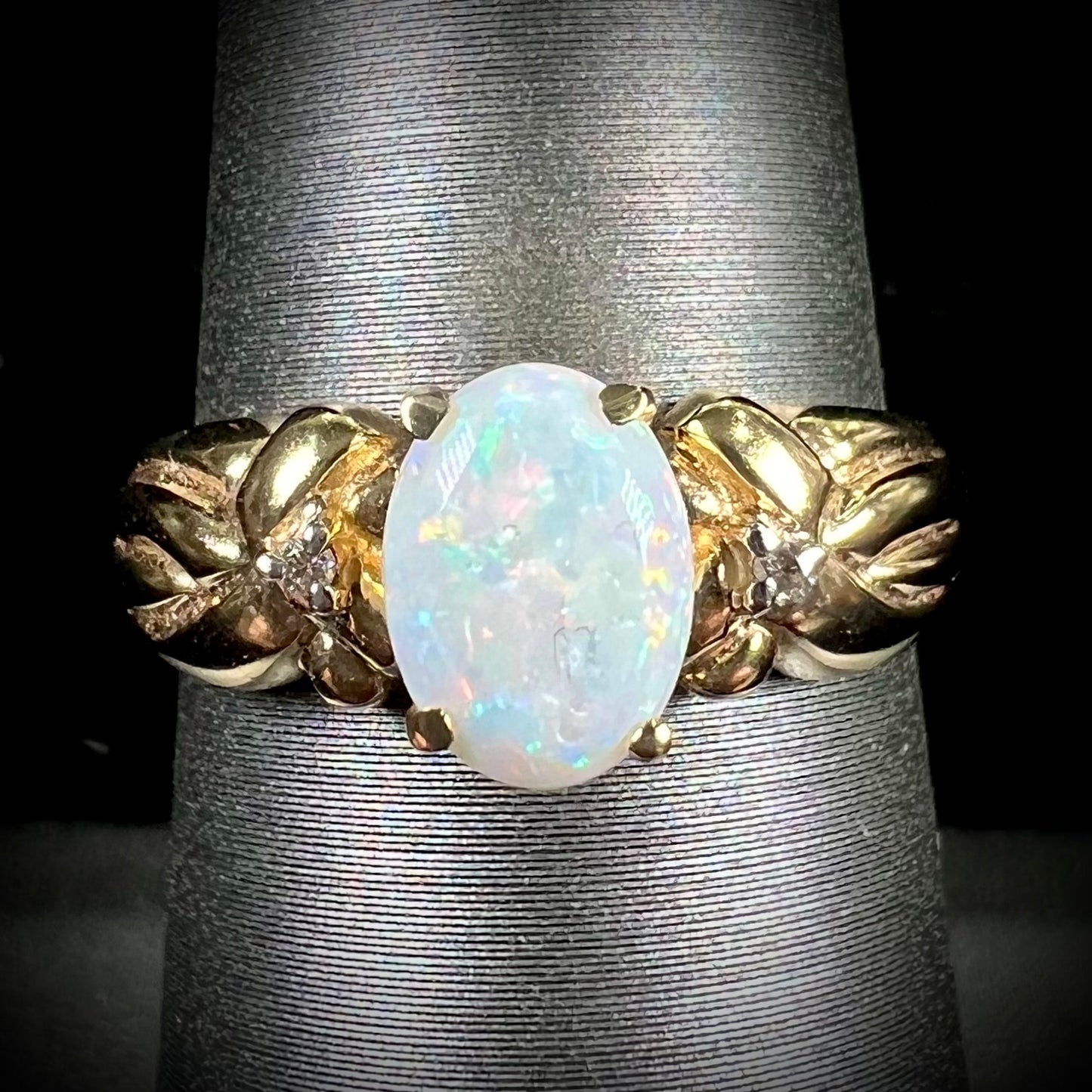 A ladies' yellow gold white crystal opal and diamond ring. The opal is prong set.