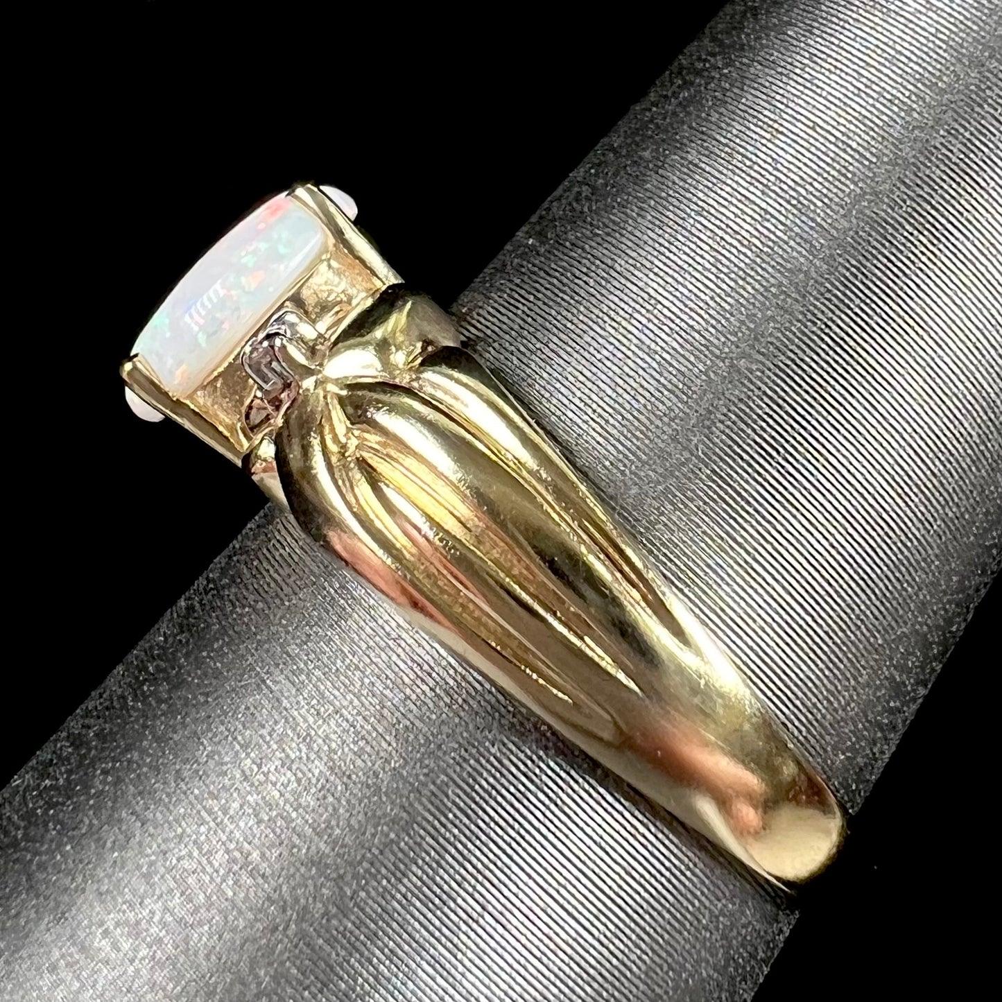 A ladies' yellow gold white crystal opal and diamond ring. The opal is prong set.