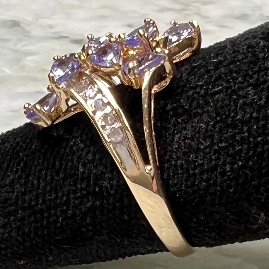 A pear shape tanzanite cluster ring channel set with diamonds in yellow gold.