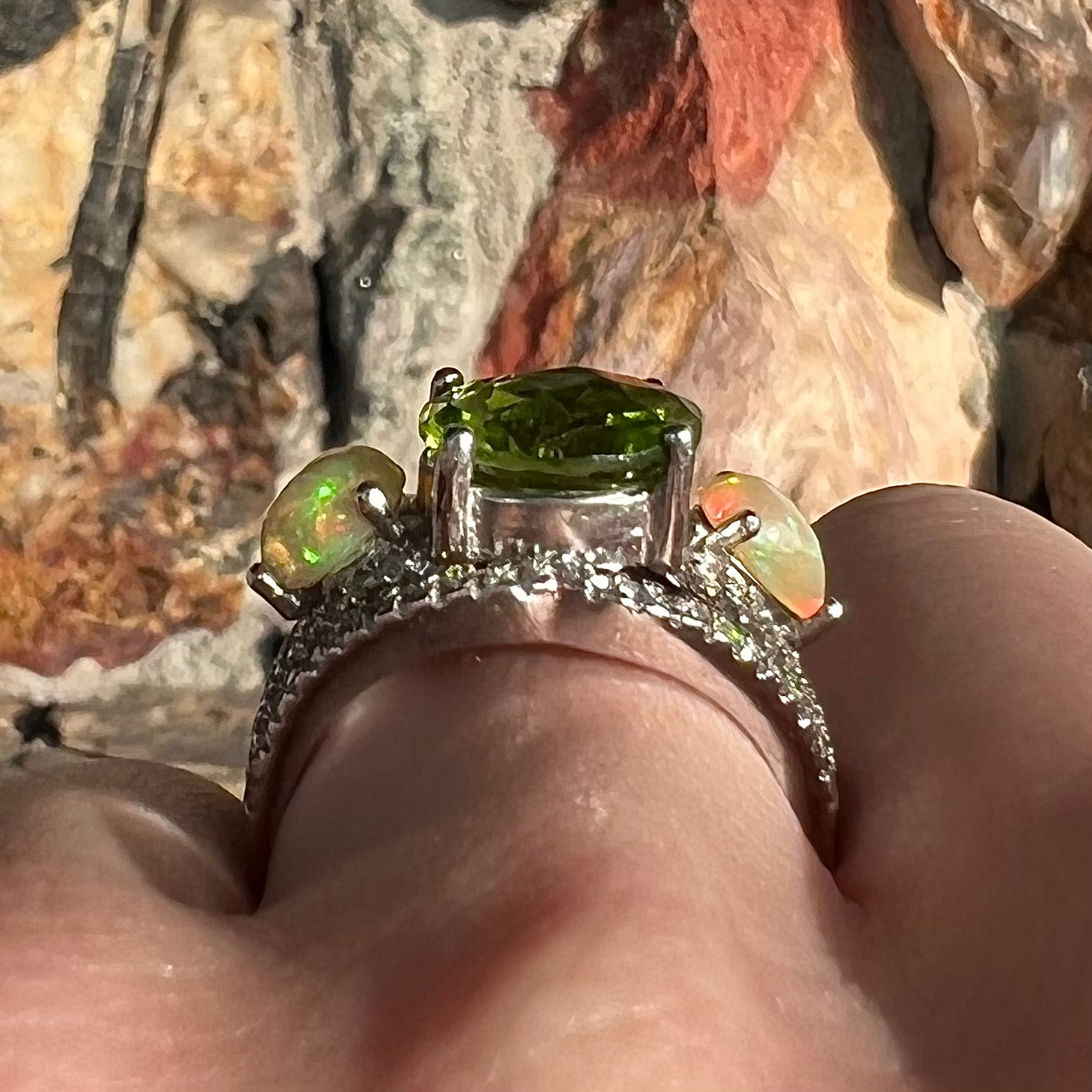 A sterling silver ring set with one large round peridot stone set between two pear shape cabochon Ethiopian opals. Cubic zirconia stones line the ring.