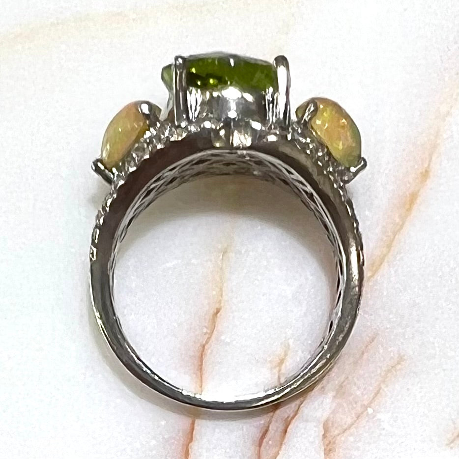 A sterling silver ring set with one large round peridot stone set between two pear shape cabochon Ethiopian opals. Cubic zirconia stones line the ring.