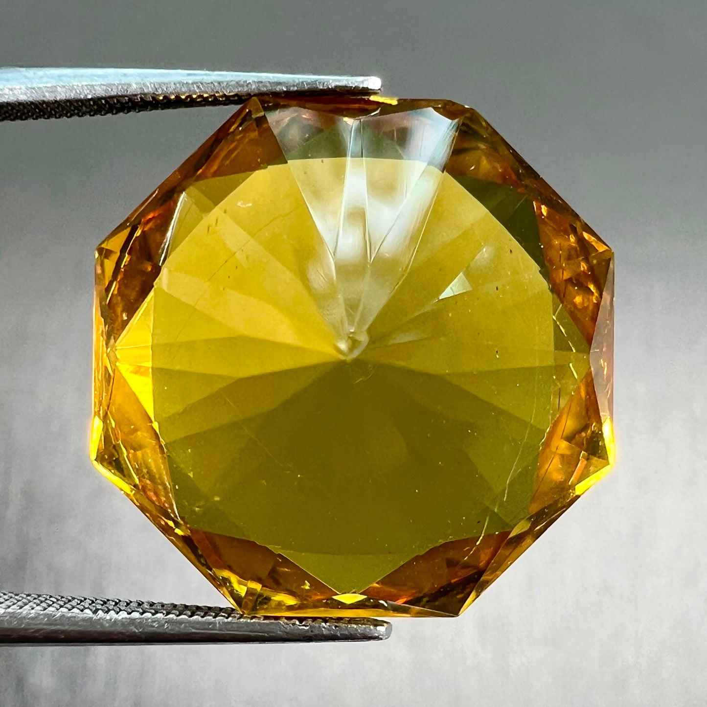 A loose, faceted octagonal cut golden amber stone. There are no bug inclusions visible.