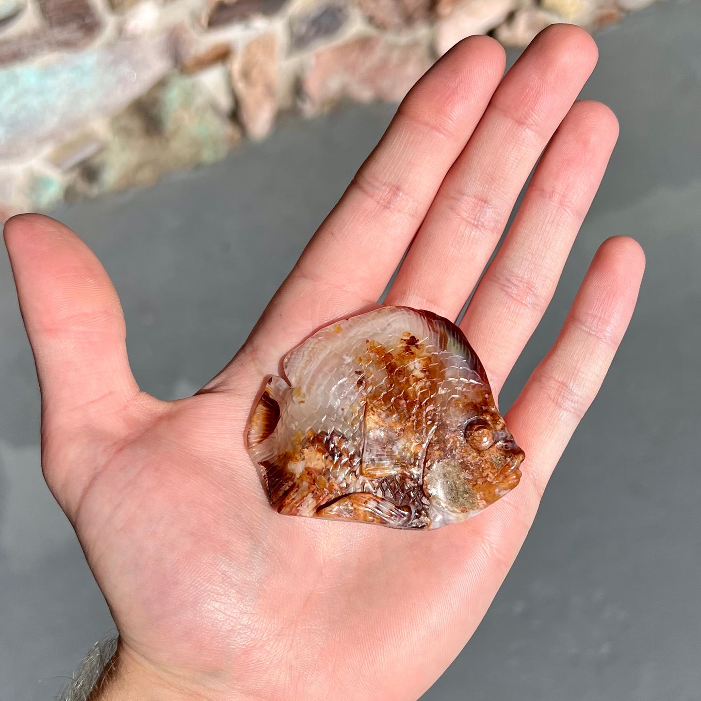 A stone fish carved from Northern Mexican fire agate. The material is brown and white.