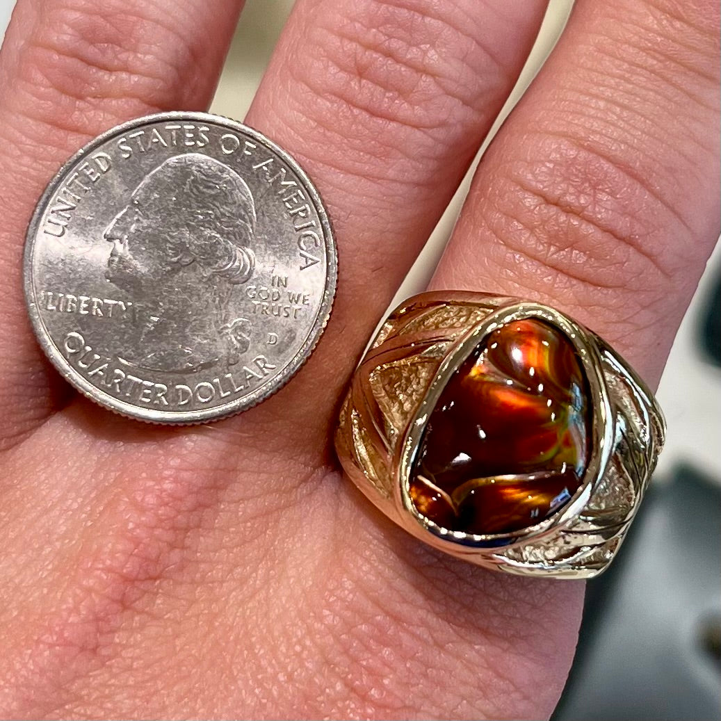 A solid, yellow gold men's fire agate ring. The predominant color is red with green undertones.