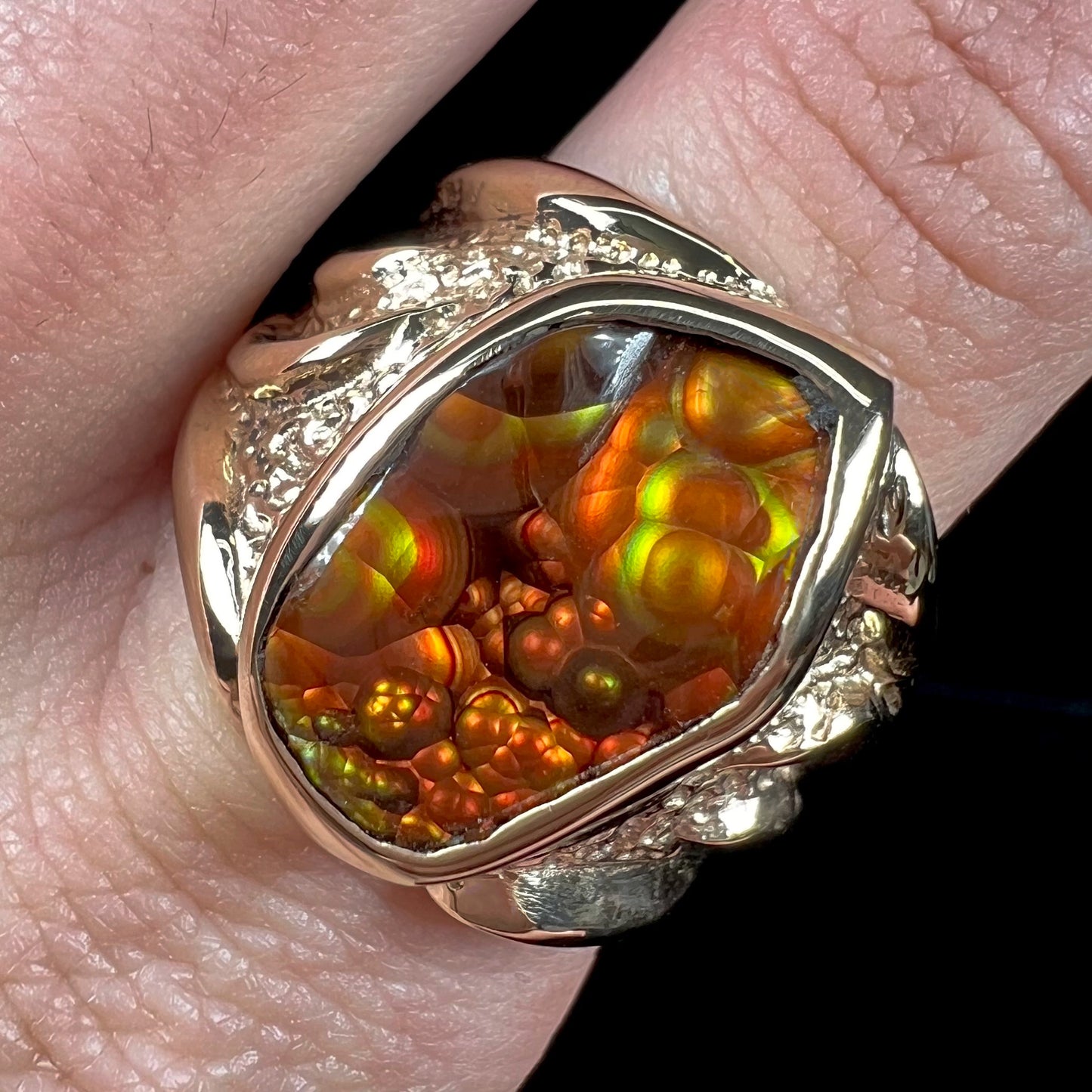 A men's yellow gold fire agate solitaire ring. The stone has a botryoidal pattern with sagenite inclusions.