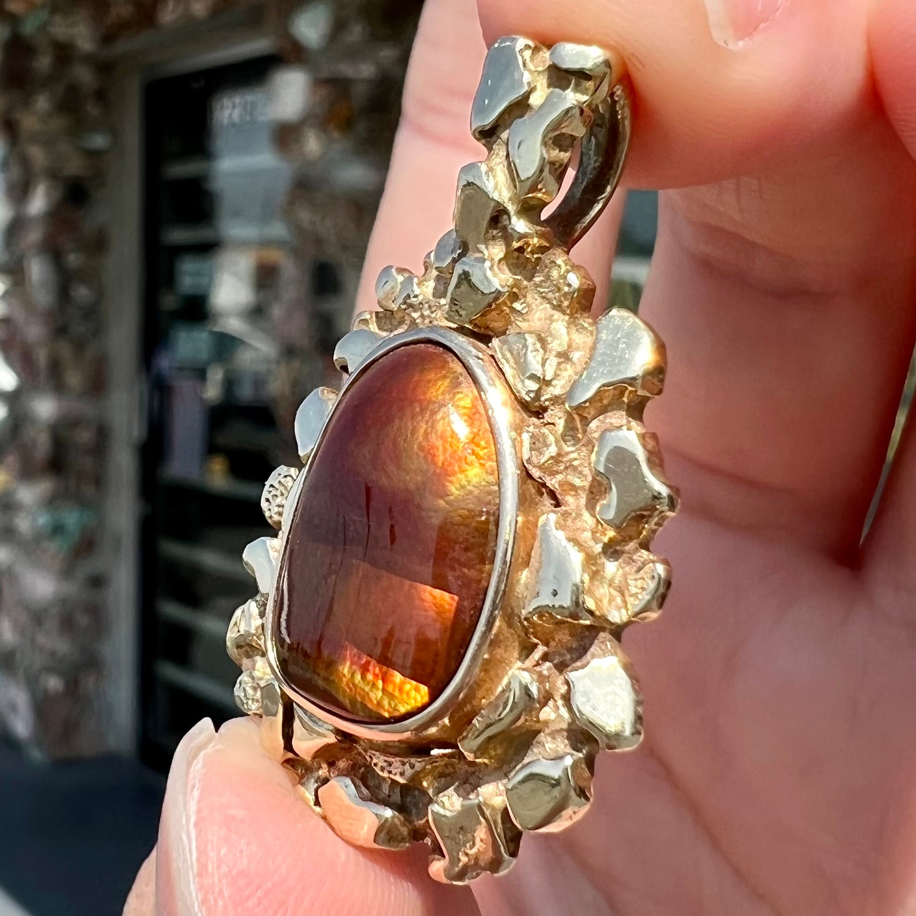 A gold nugget style pendant set with a freeform cabochon cut fire agate stone.