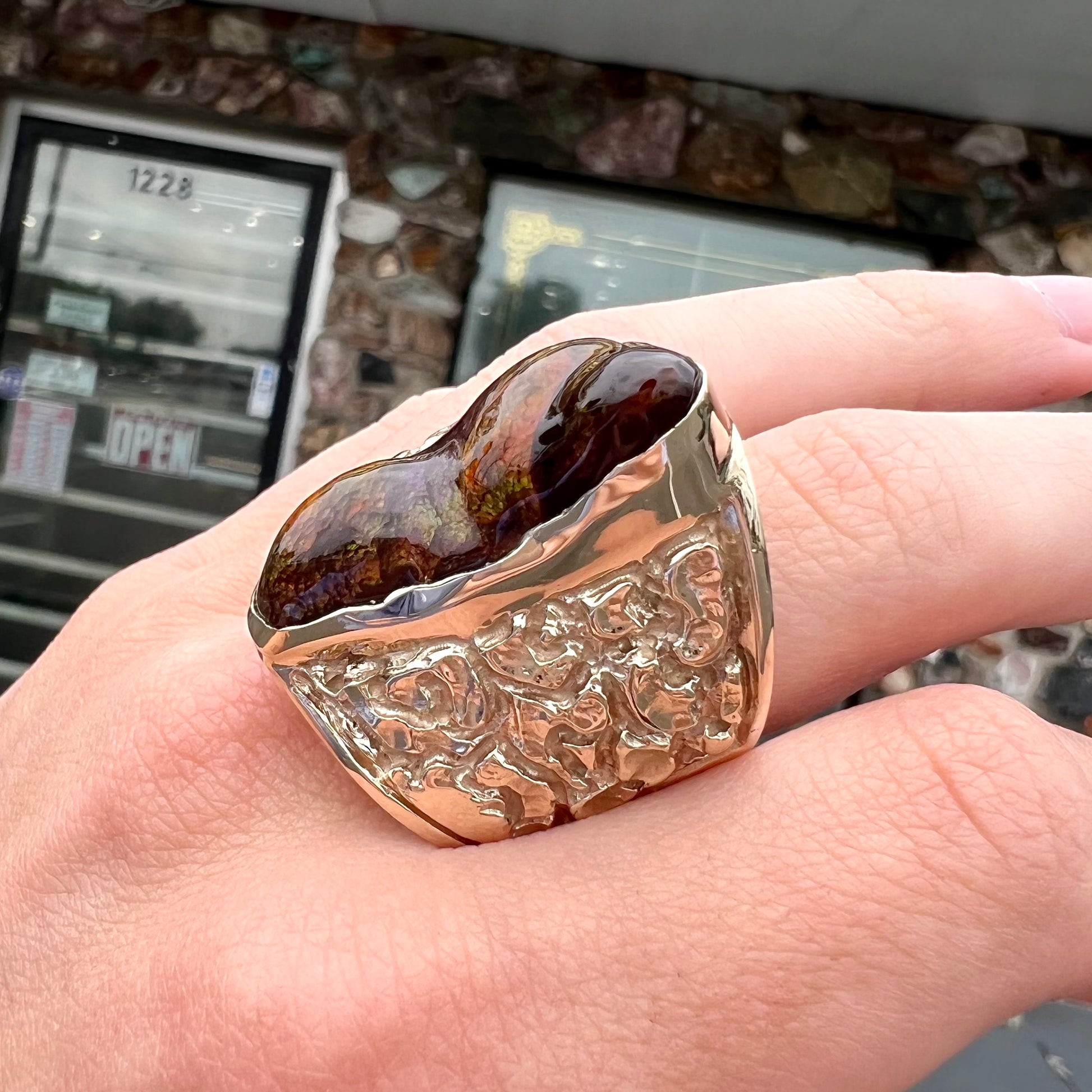 A large nugget style men's fire agate ring cast in yellow gold.  The fire agate is predominantly orange and green.