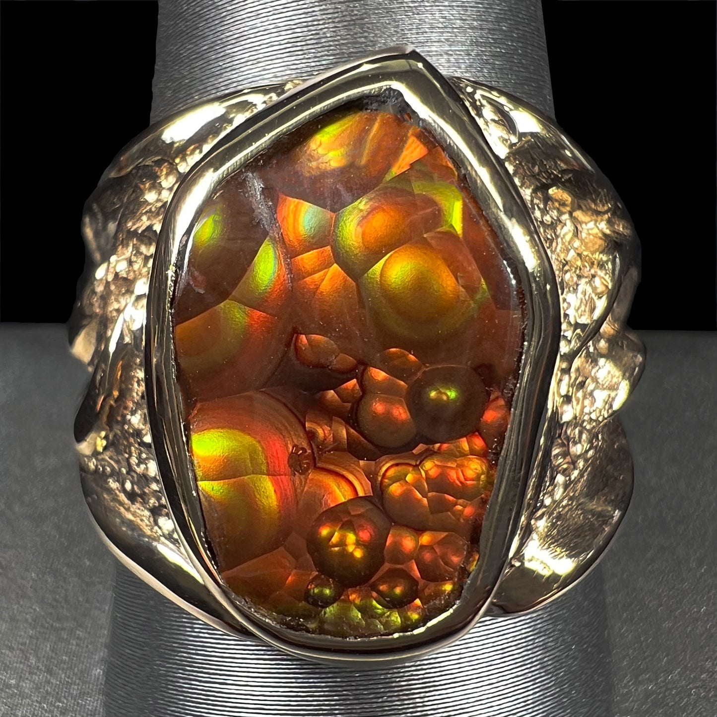 A men's yellow gold fire agate solitaire ring. The stone has a botryoidal pattern with sagenite inclusions.