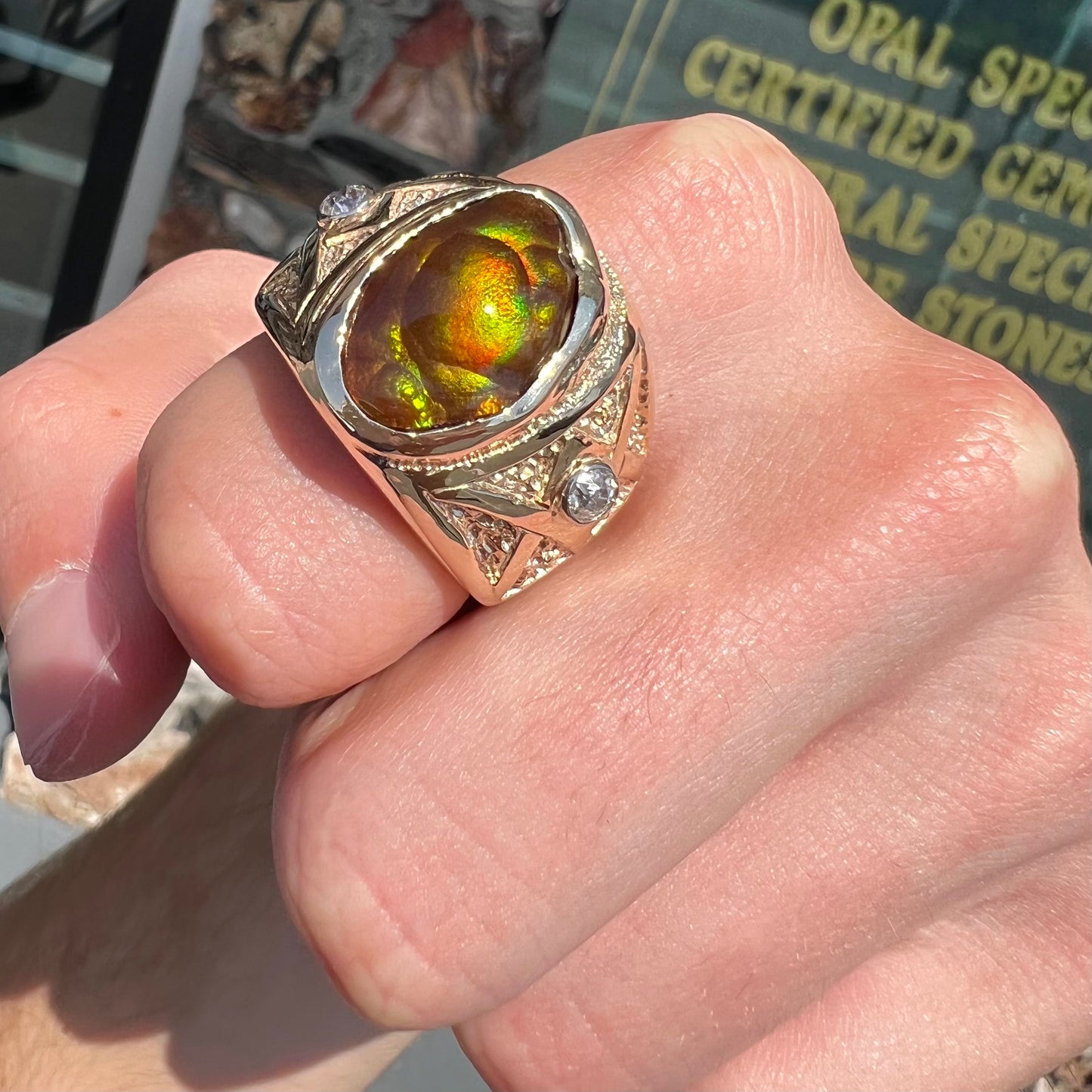 A men's solid yellow gold fire agate and diamond ring. The fire agate displays predominantly red and green.