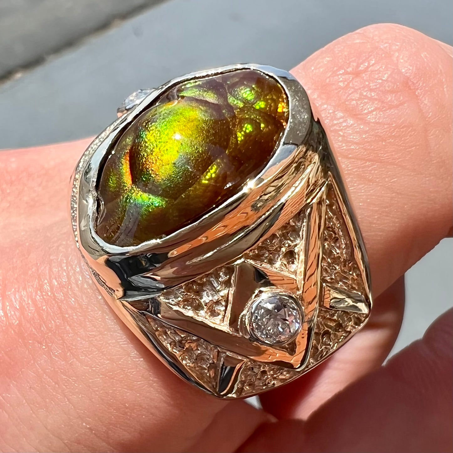 A men's solid yellow gold fire agate and diamond ring. The fire agate displays predominantly red and green.