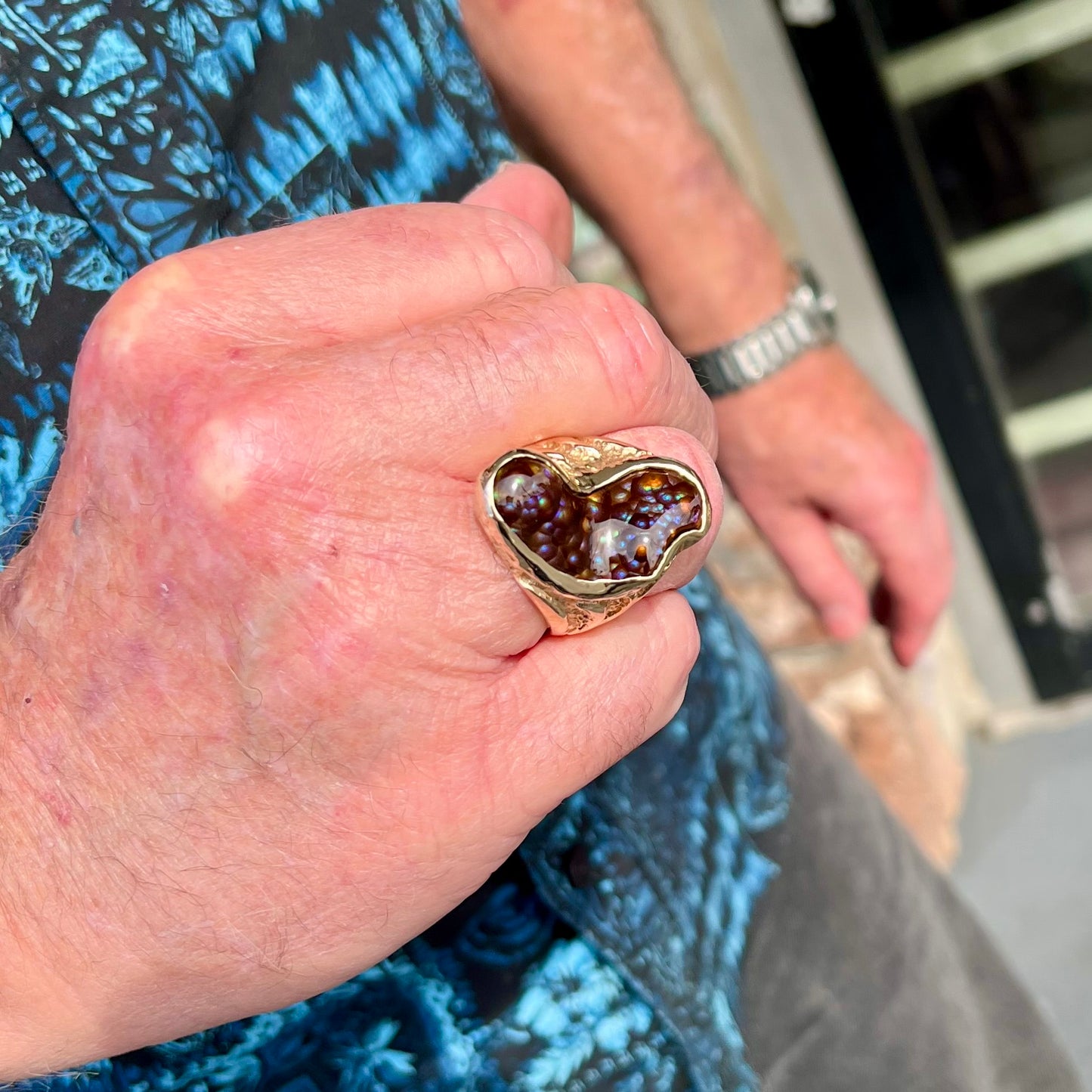 A men's Deer Creek fire agate solitaire ring cast in yellow gold. The stone is predominantly purple.