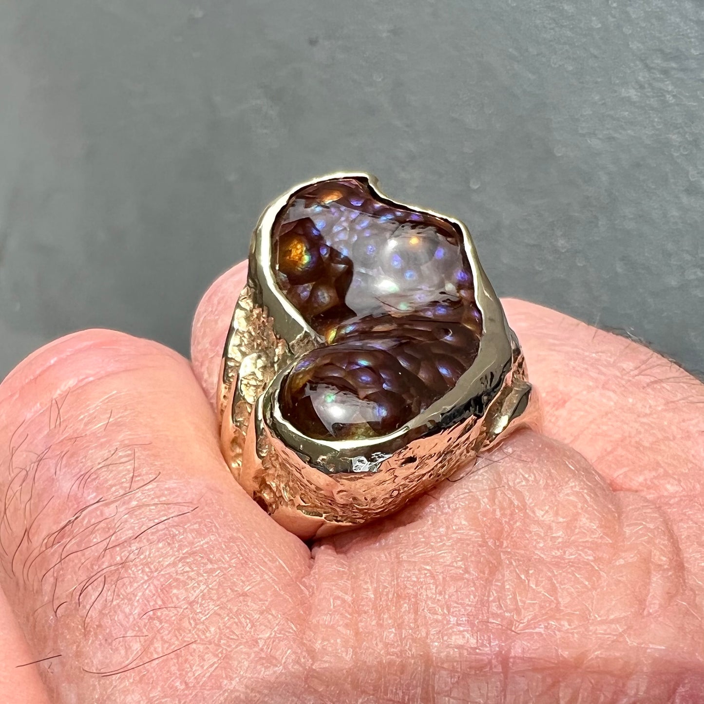 A men's Deer Creek fire agate solitaire ring cast in yellow gold. The stone is predominantly purple.