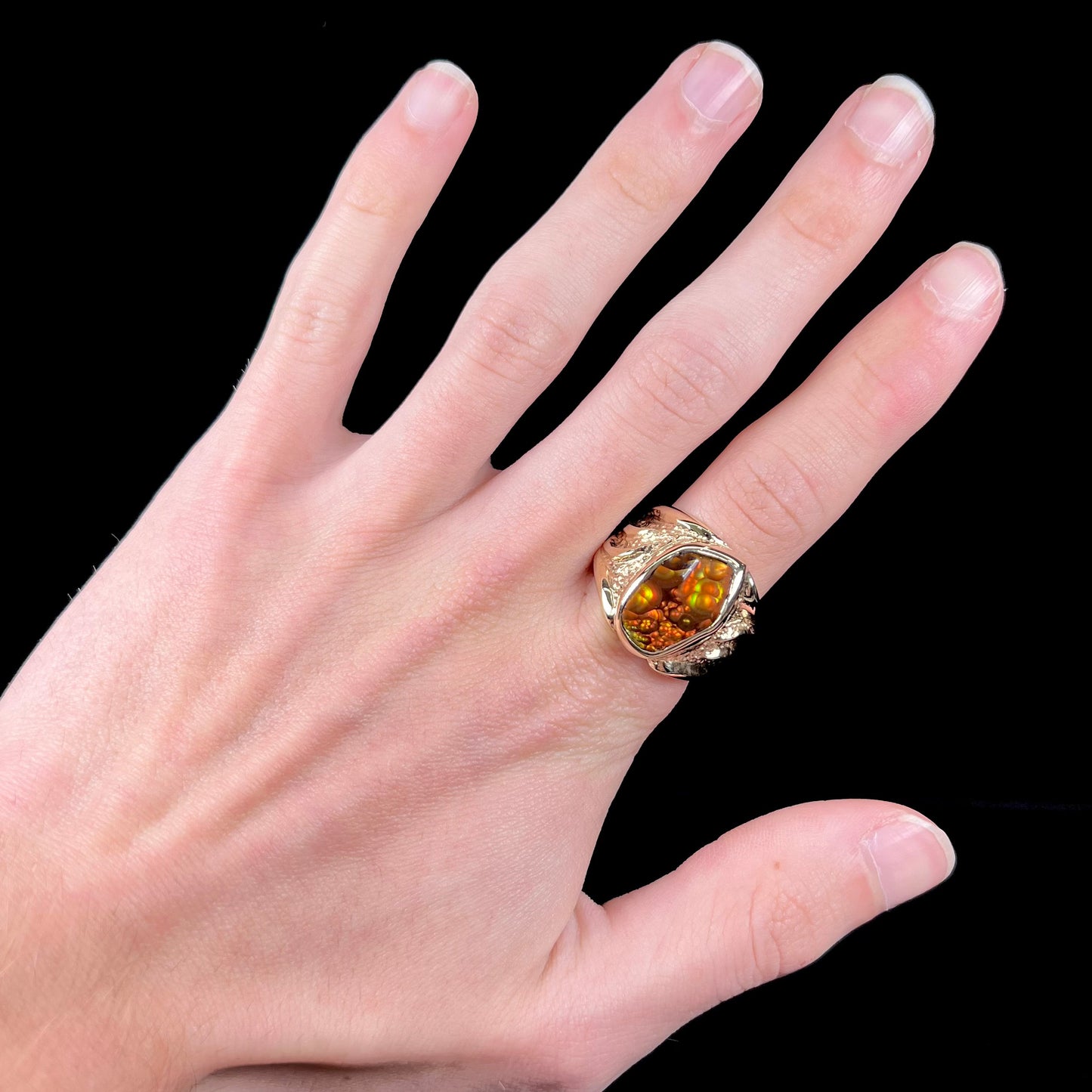 A men's yellow gold fire agate solitaire ring. The stone has a botryoidal pattern with sagenite inclusions.