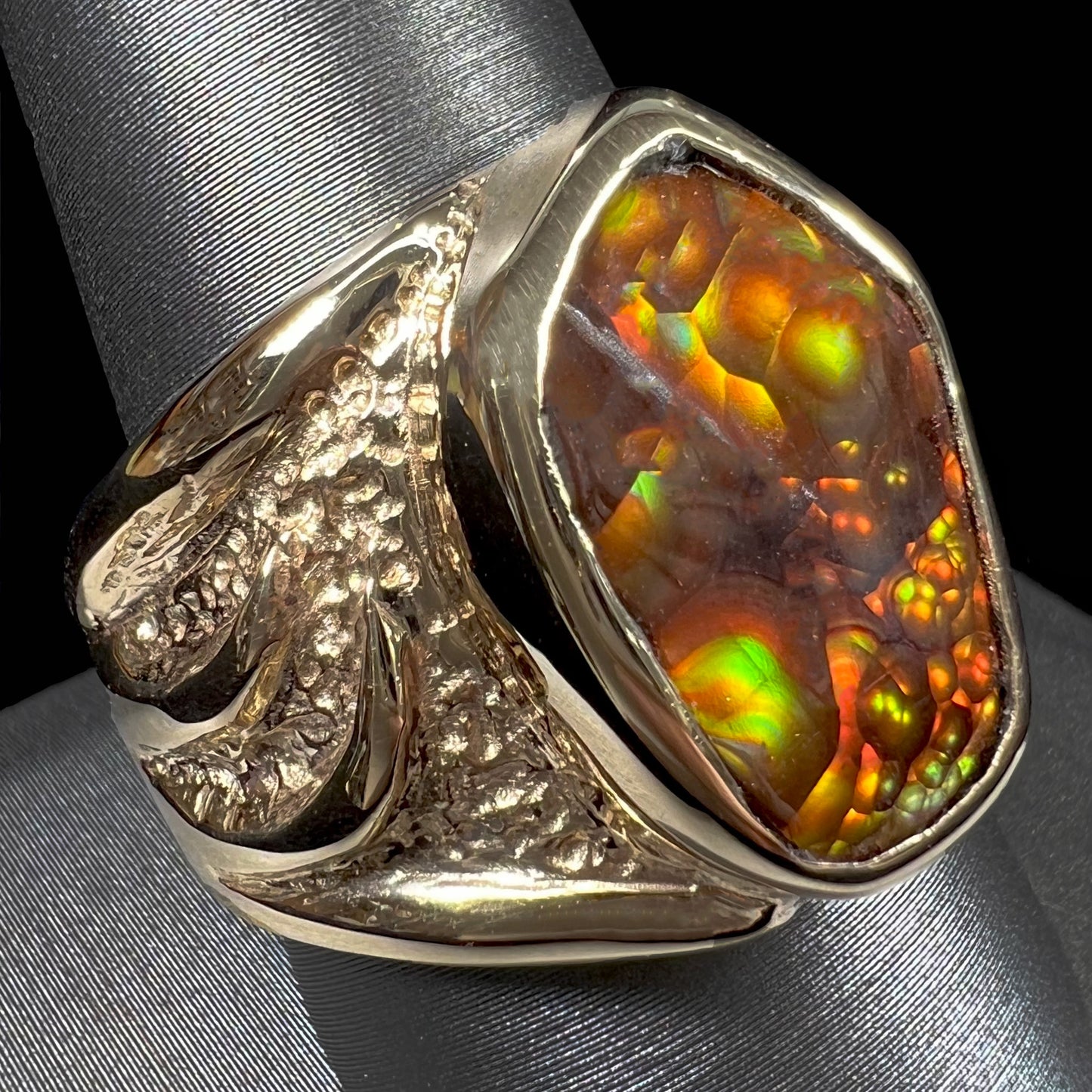 A men's yellow gold fire agate solitaire ring. The stone has a botryoidal pattern with sagenite inclusions.