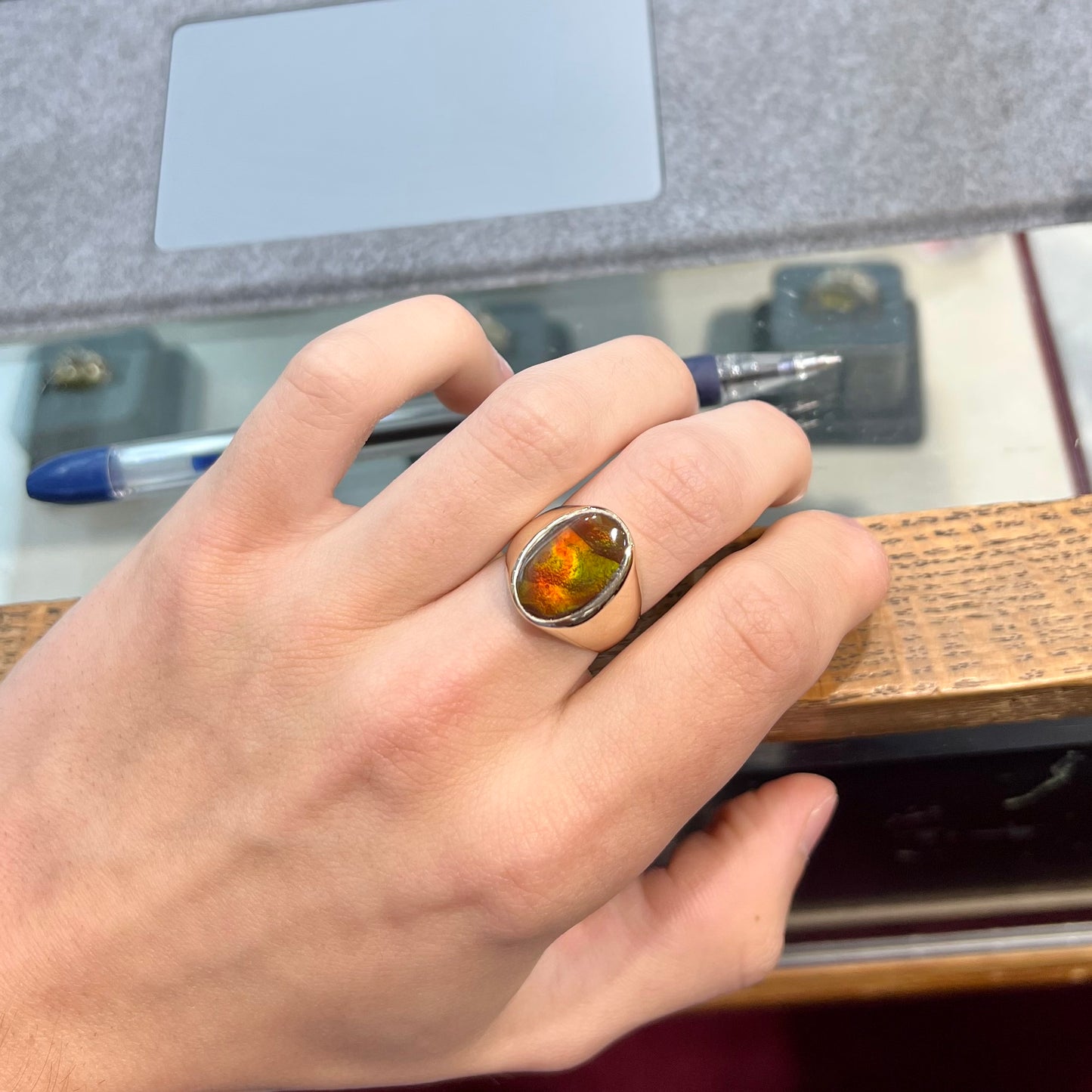 A yellow gold solitaire fire agate men's ring. The fire agate is oval shape, and red and green in color.