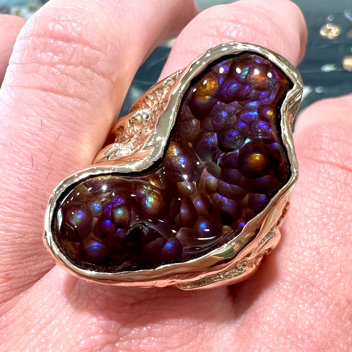 A men's Deer Creek fire agate solitaire ring cast in yellow gold. The stone is predominantly purple.
