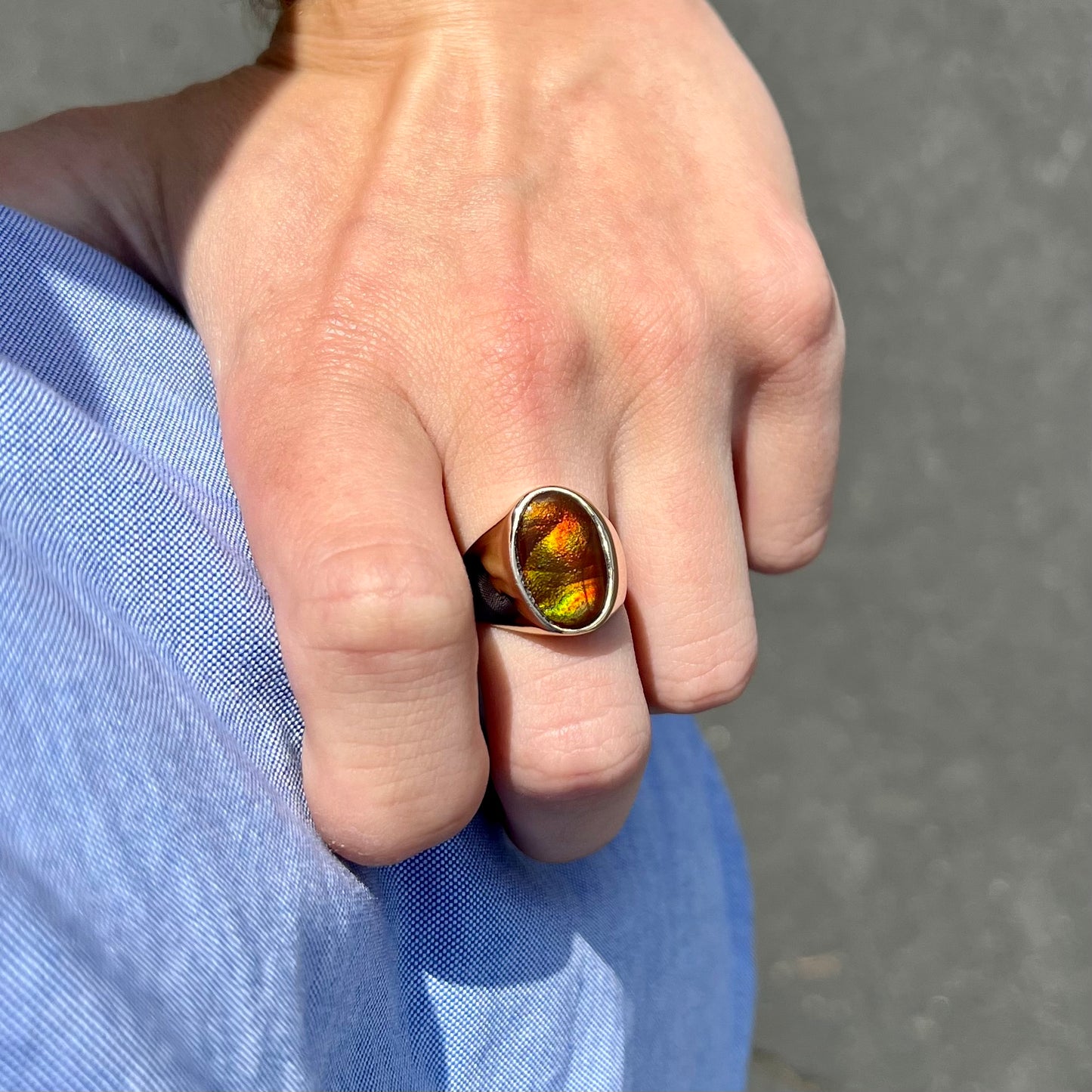 A yellow gold solitaire fire agate men's ring. The fire agate is oval shape, and red and green in color.