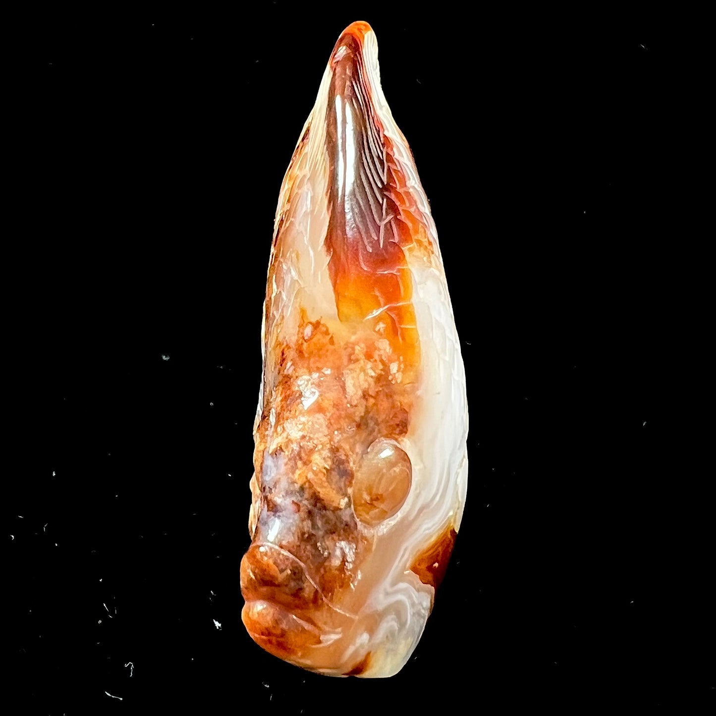A stone fish carved from Northern Mexican fire agate. The material is brown and white.