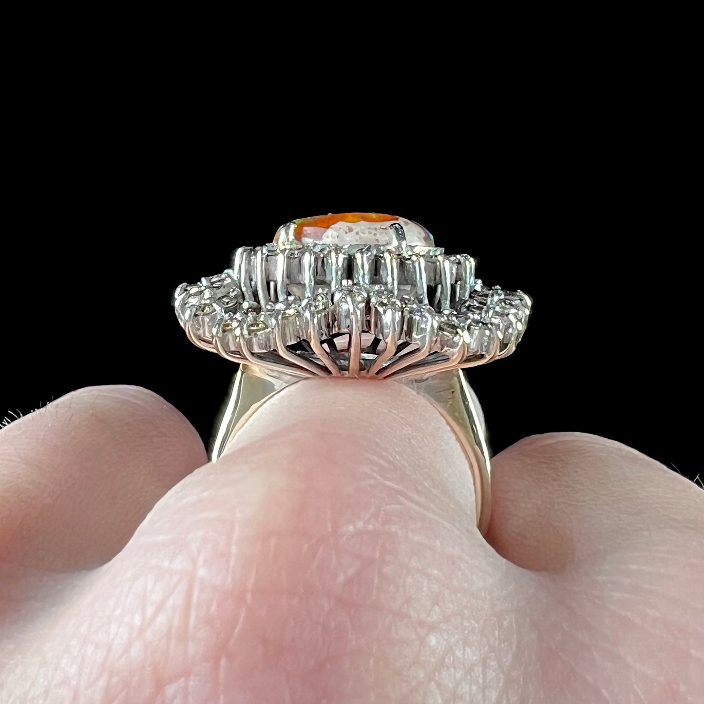 An 18k white gold orange fire opal ring set with a triple halo of diamonds.