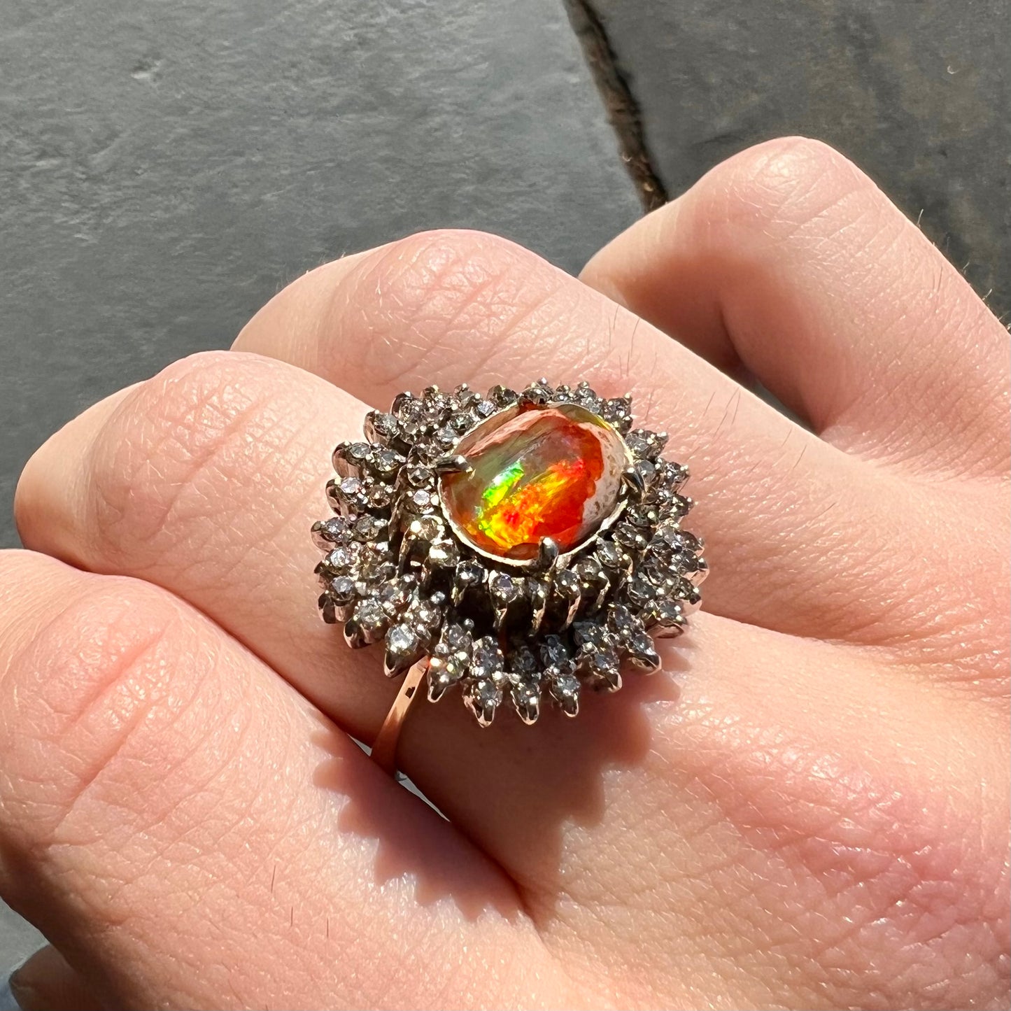 An 18k white gold orange fire opal ring set with a triple halo of diamonds.