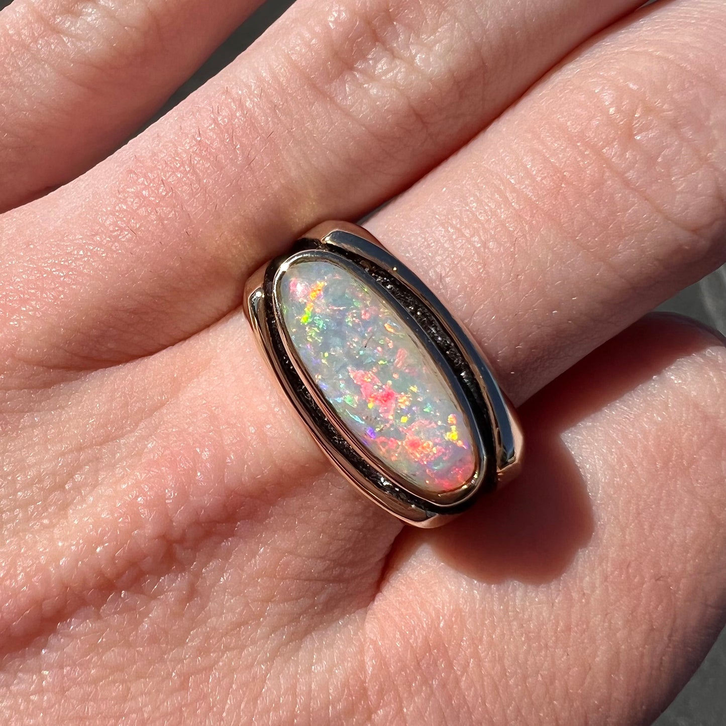 An Australian white crystal opal men's ring in solid yellow gold. The recesses of the ring have been blackened.