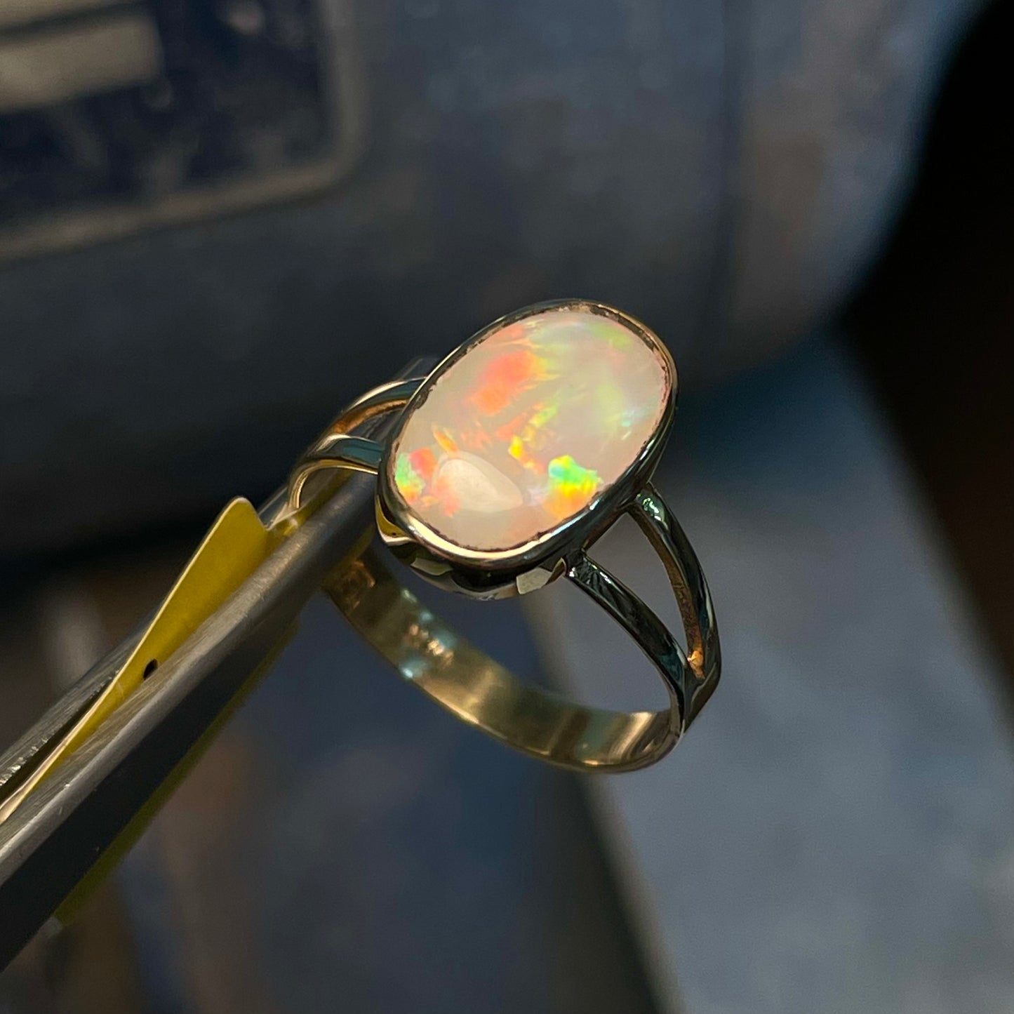 A handmade split shank white opal solitaire ring in yellow gold.