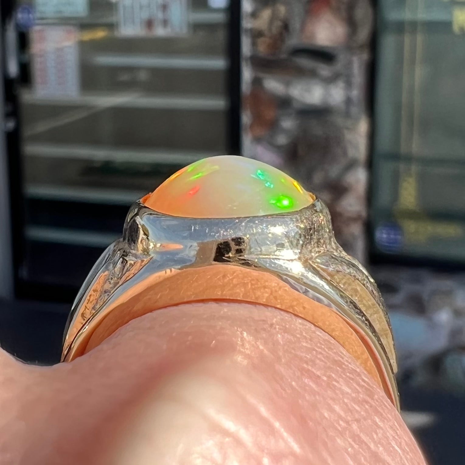 A solid yellow gold solitaire men's fire opal ring.  The stone is an orange oval cabochon cut.