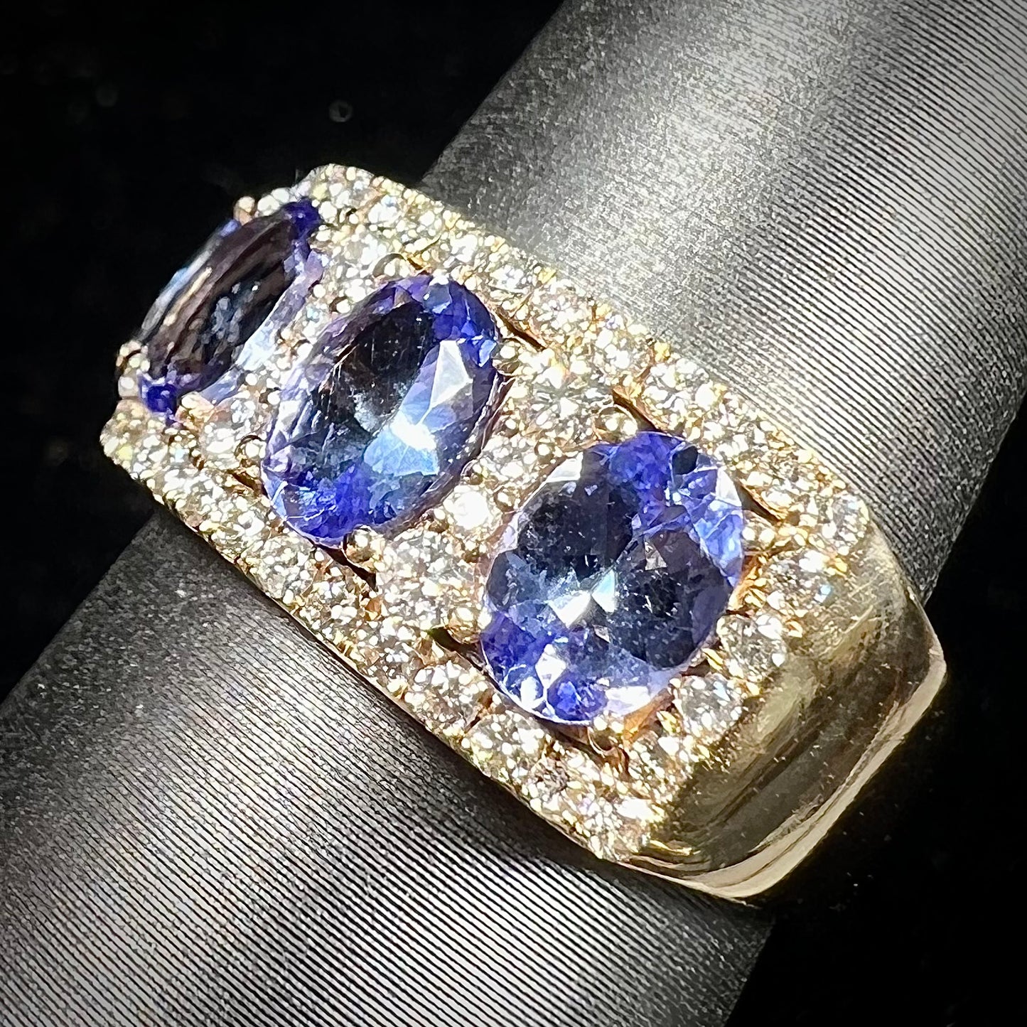 A gold and diamond ladies' band set with five oval cut tanzanite stones.