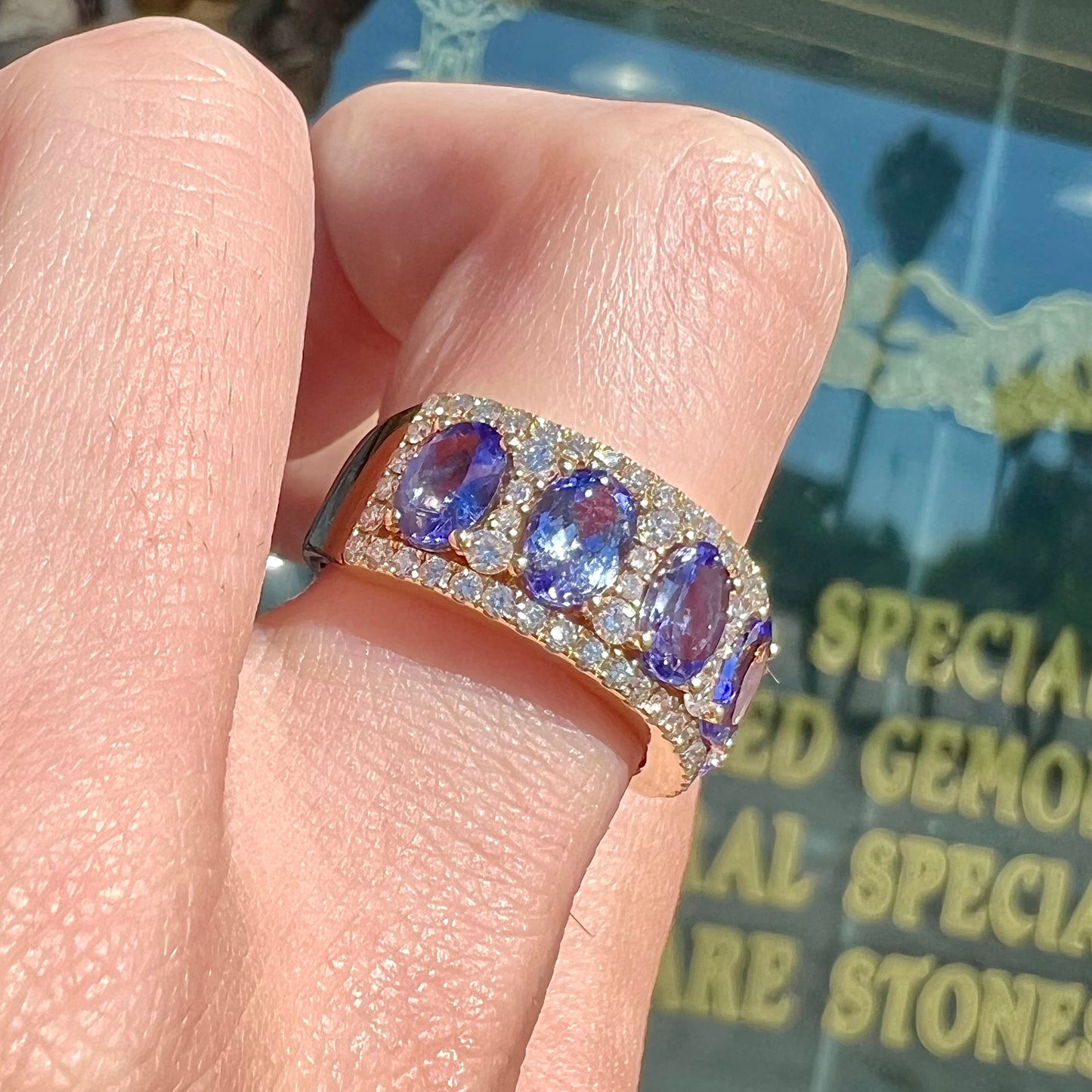 A gold and diamond ladies' band set with five oval cut tanzanite stones.