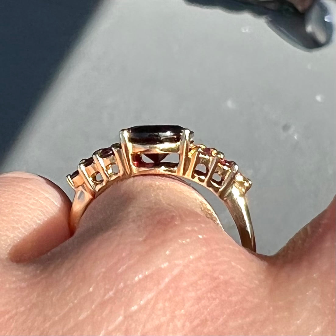 A yellow gold ring set with clusters of purple garnets set on each side of a rhodolite garnet.