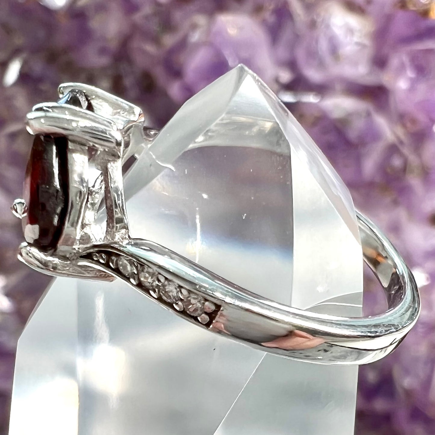 A sterling silver ring set with two faceted heart shape red almandine garnet stones.