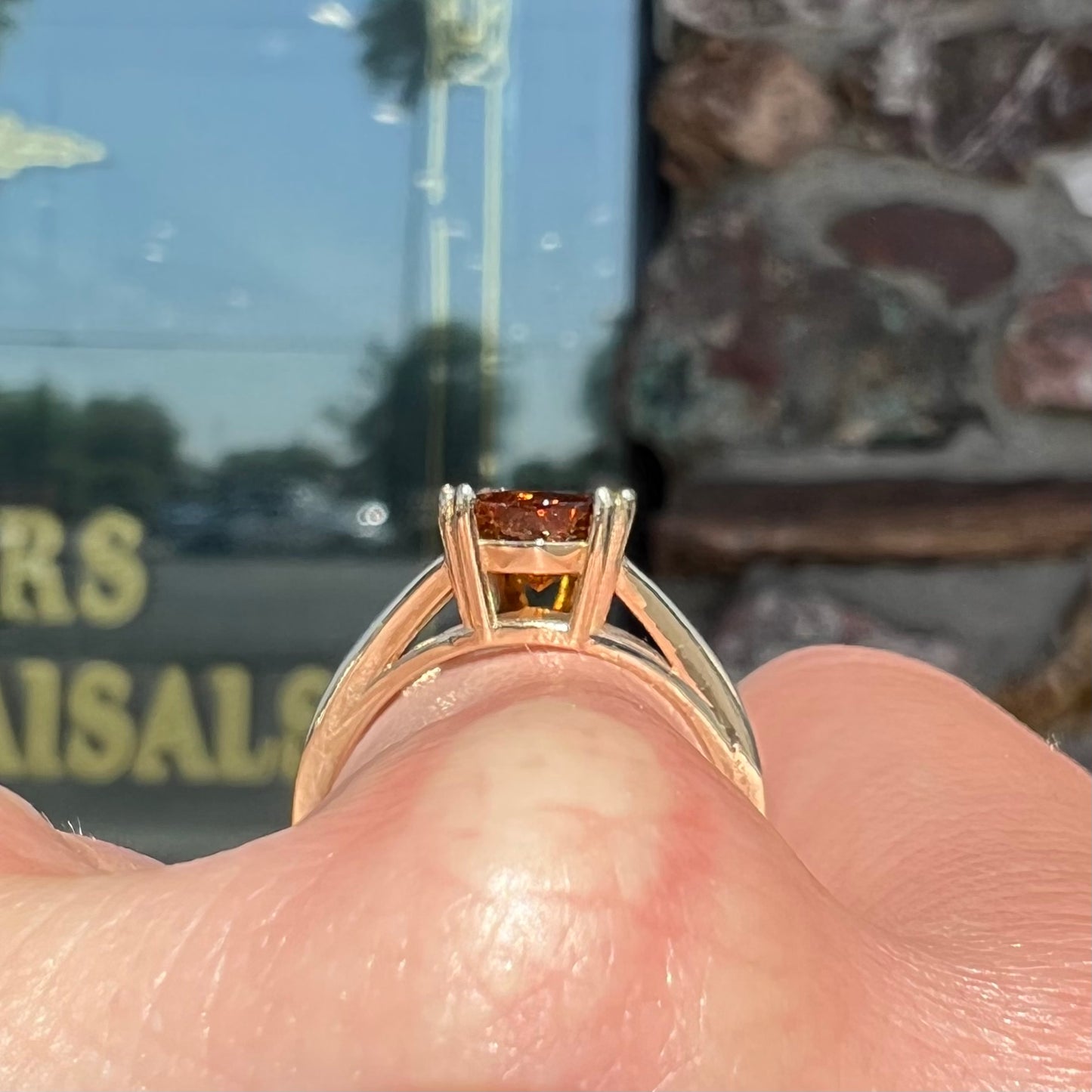 A gold split Euro shank solitaire ring set with an orange pear shape hessonite garnet stone.