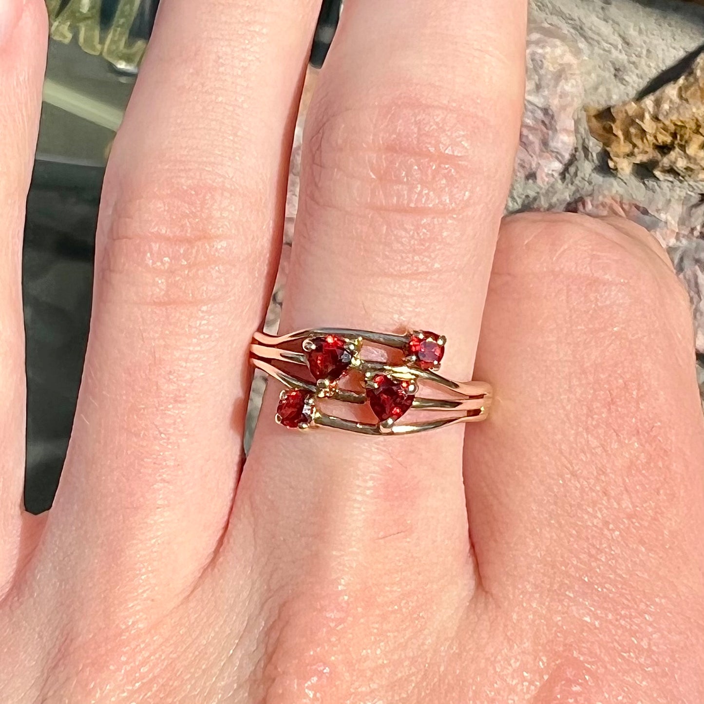 A yellow gold multishank ring set with two heart shape and two round cut red garnets.