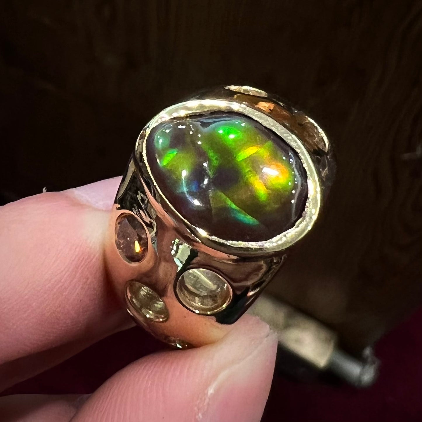 Men's rainbow fire agate ring set in yellow gold with champagne diamonds. The ring style has holes.