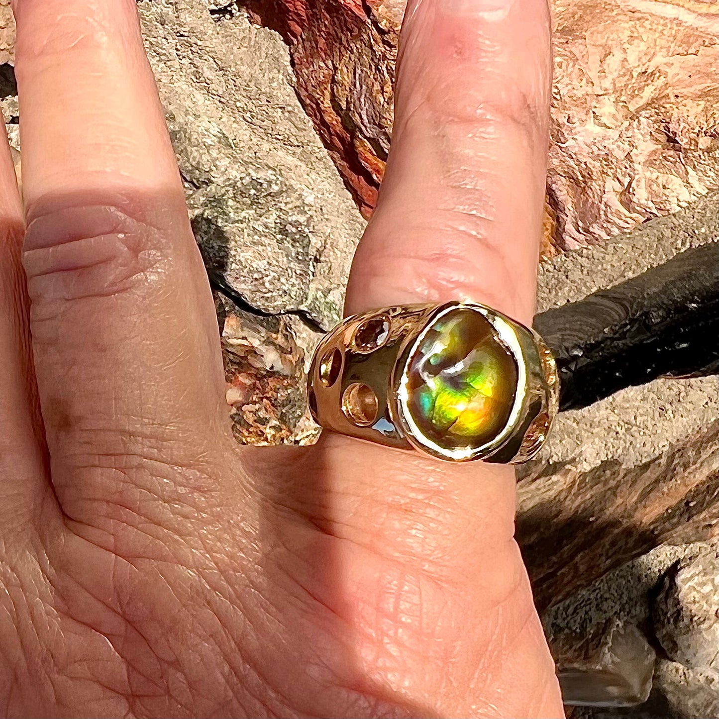 Men's rainbow fire agate ring set in yellow gold with champagne diamonds. The ring style has holes.