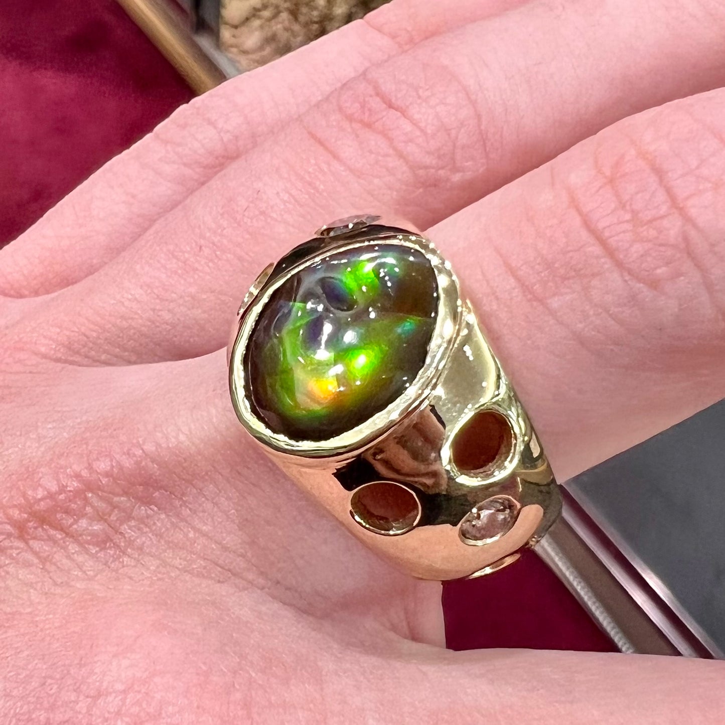 Men's rainbow fire agate ring set in yellow gold with champagne diamonds. The ring style has holes.