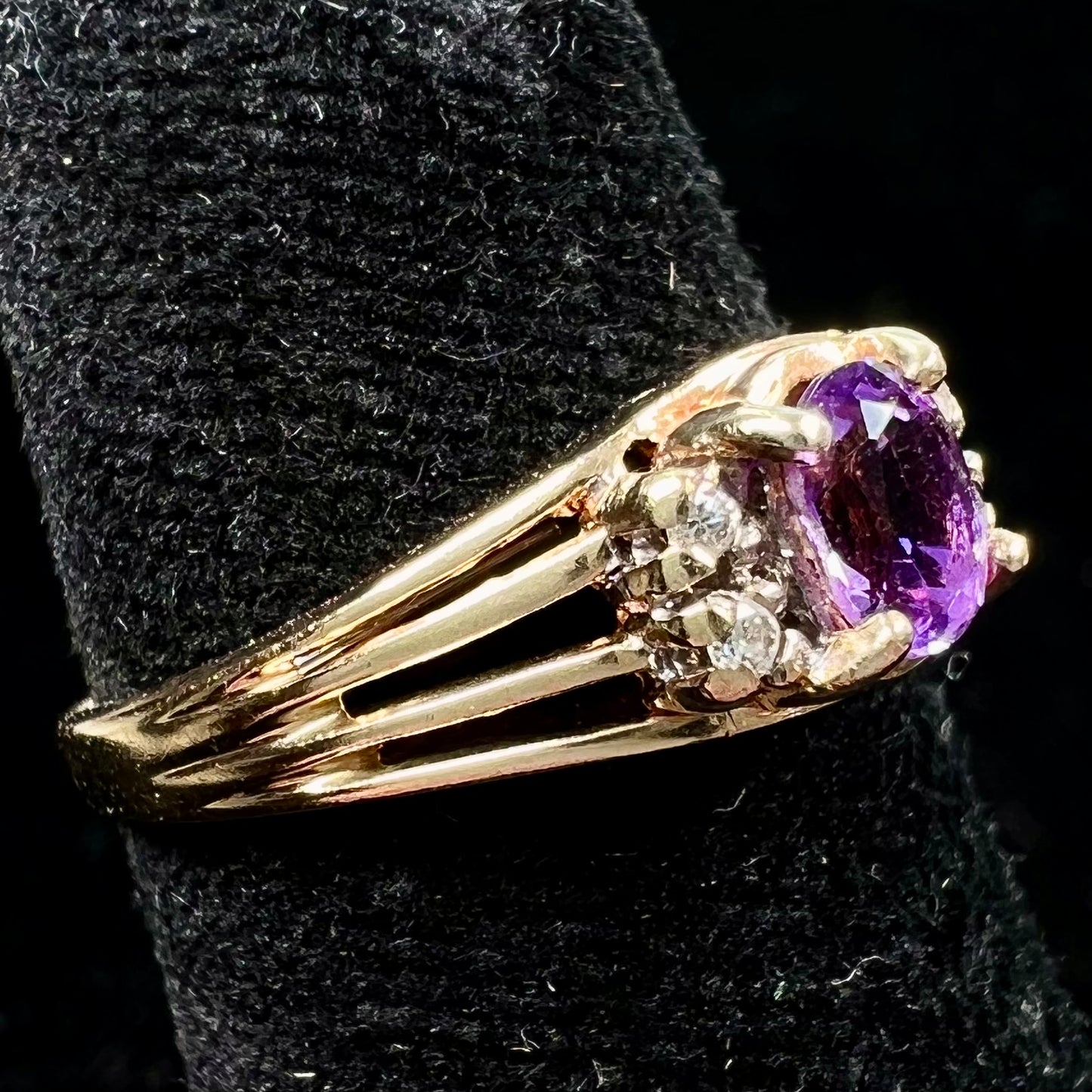 A ladies split shank gold ring set with an oval cut amethyst and round brilliant diamond accents.