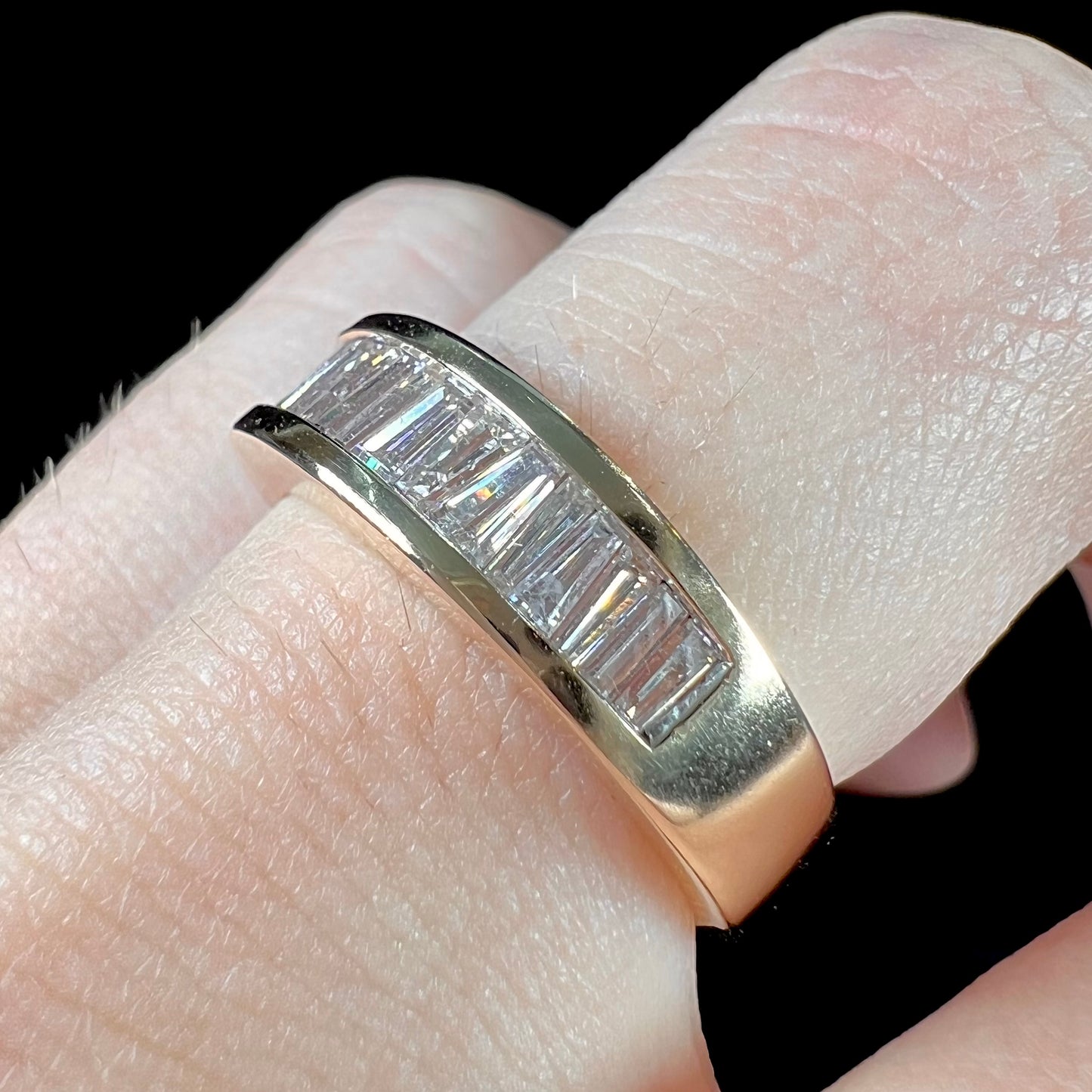 A ladies' yellow gold ring channel set with a row of baguette cut diamonds.