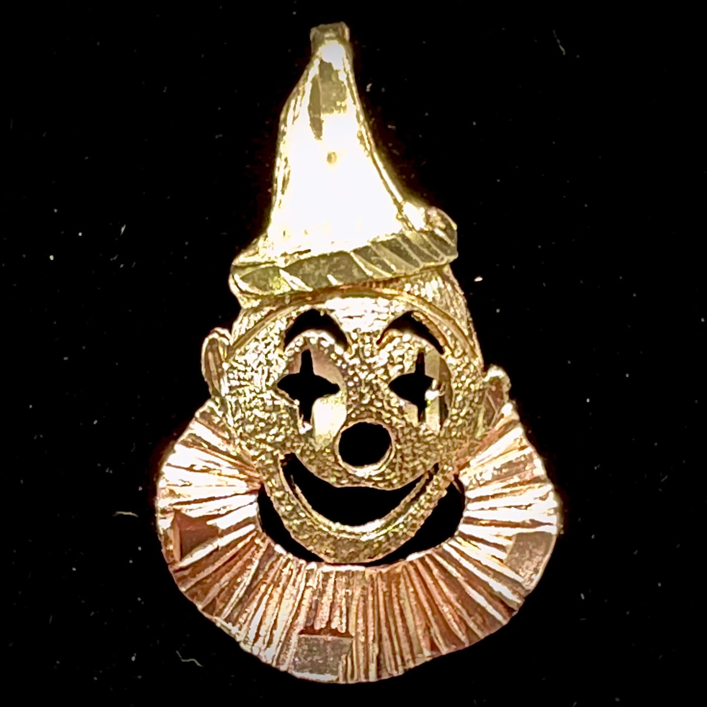 A small gold clown pendant charm. The clown's face and hat are yellow gold, and his neck frills are rose gold.