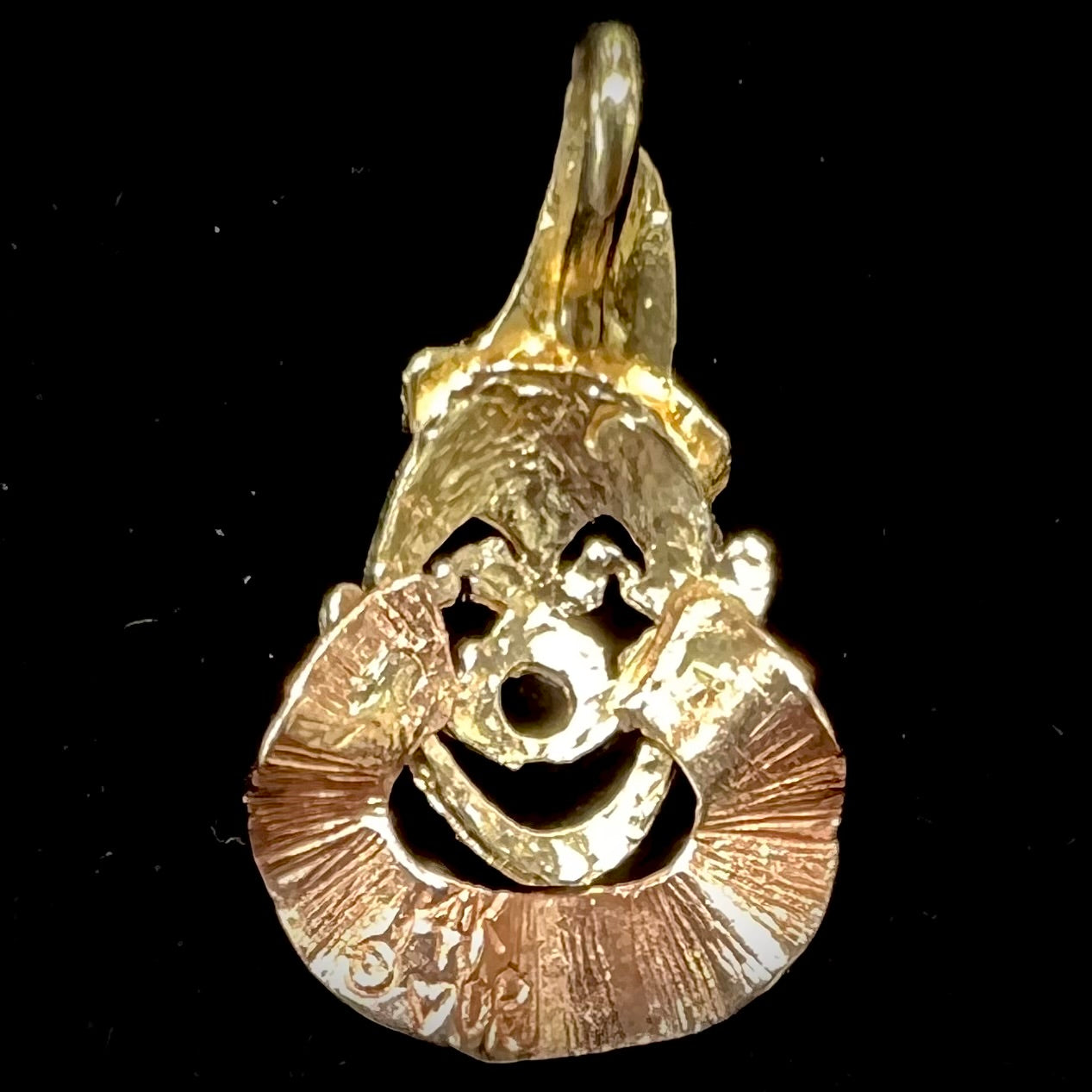 A small gold clown pendant charm. The clown's face and hat are yellow gold, and his neck frills are rose gold.